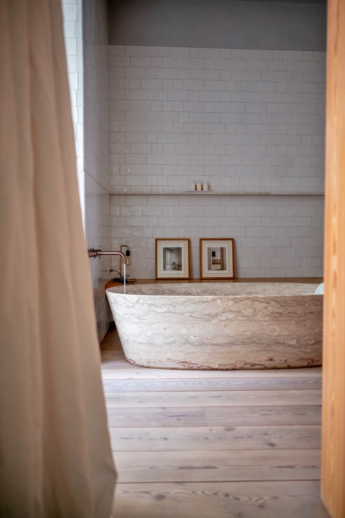 Santa Clara 1728, Portugal — marble soaking tub with subway tile surround, wooden flooring, and minimalist bathroom design with warm natural light.