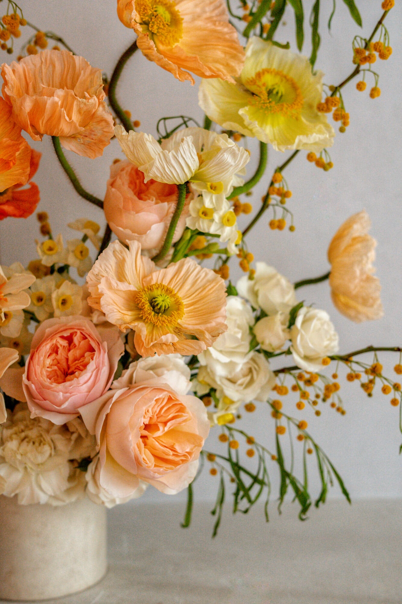 Santa Clara 1728, Portugal — Peachy ranunculus and garden roses with cream poppies and mustard hypericum in ceramic vase, soft natural light.
