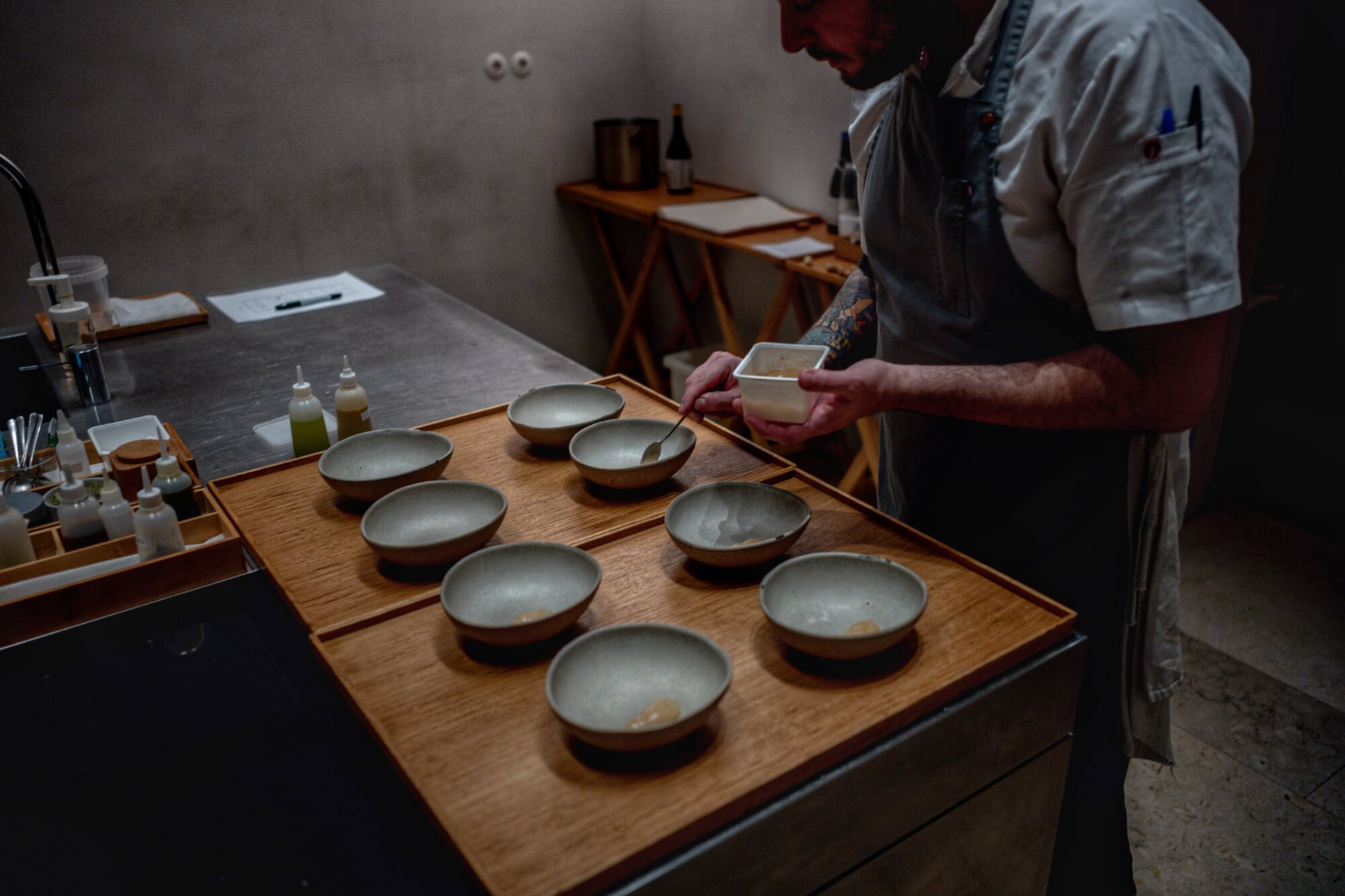 Ceia, Portugal — Tea tasting setup with nine ceramic bowls arranged on wooden table, hands holding sample cup, minimalist hospitality design.
