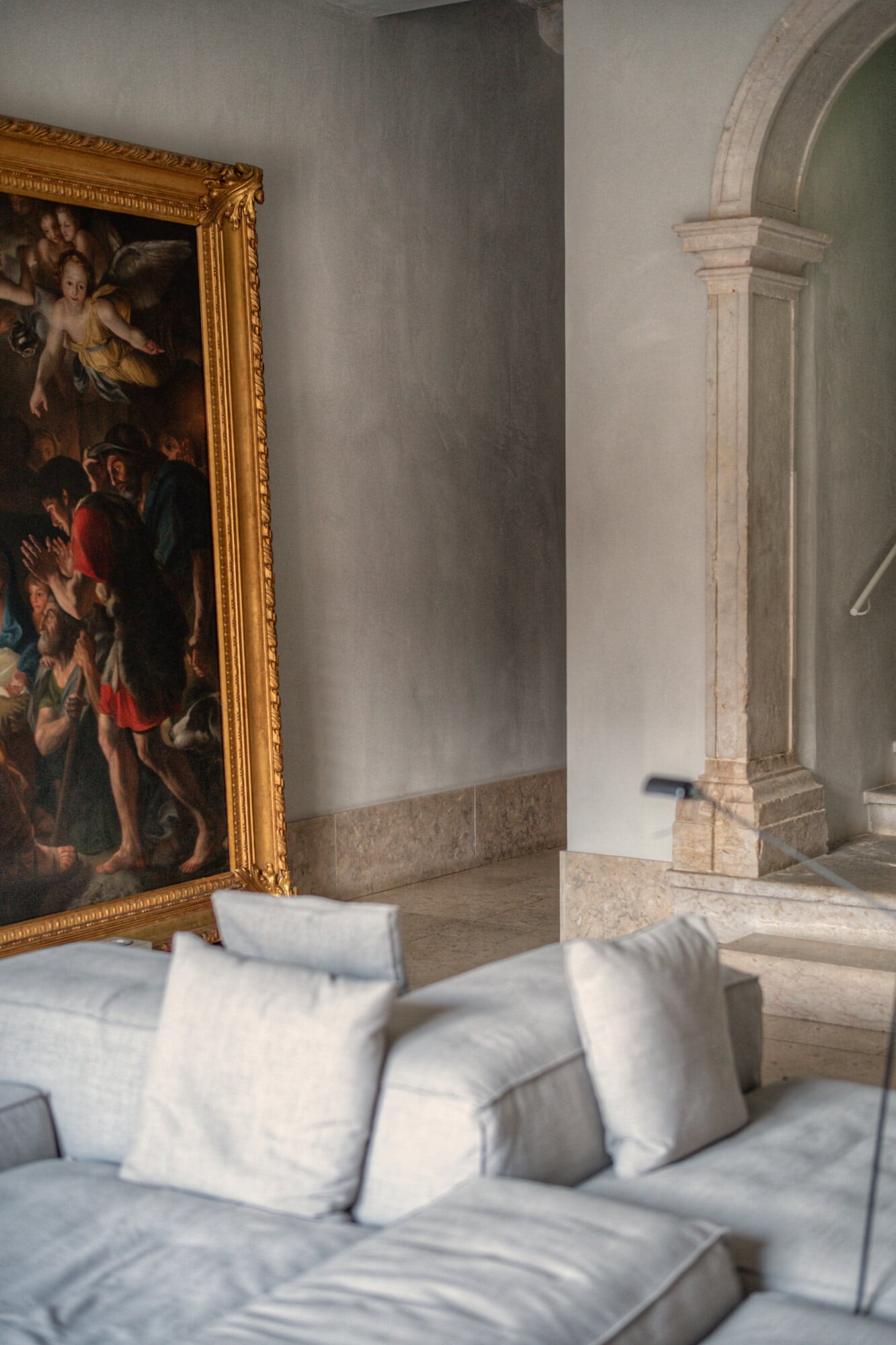 Santa Clara 1728, Portugal — Neoclassical archway with cream pillars, gilt-framed religious painting, linen sofa with white cushions, marble flooring, soft natural light.