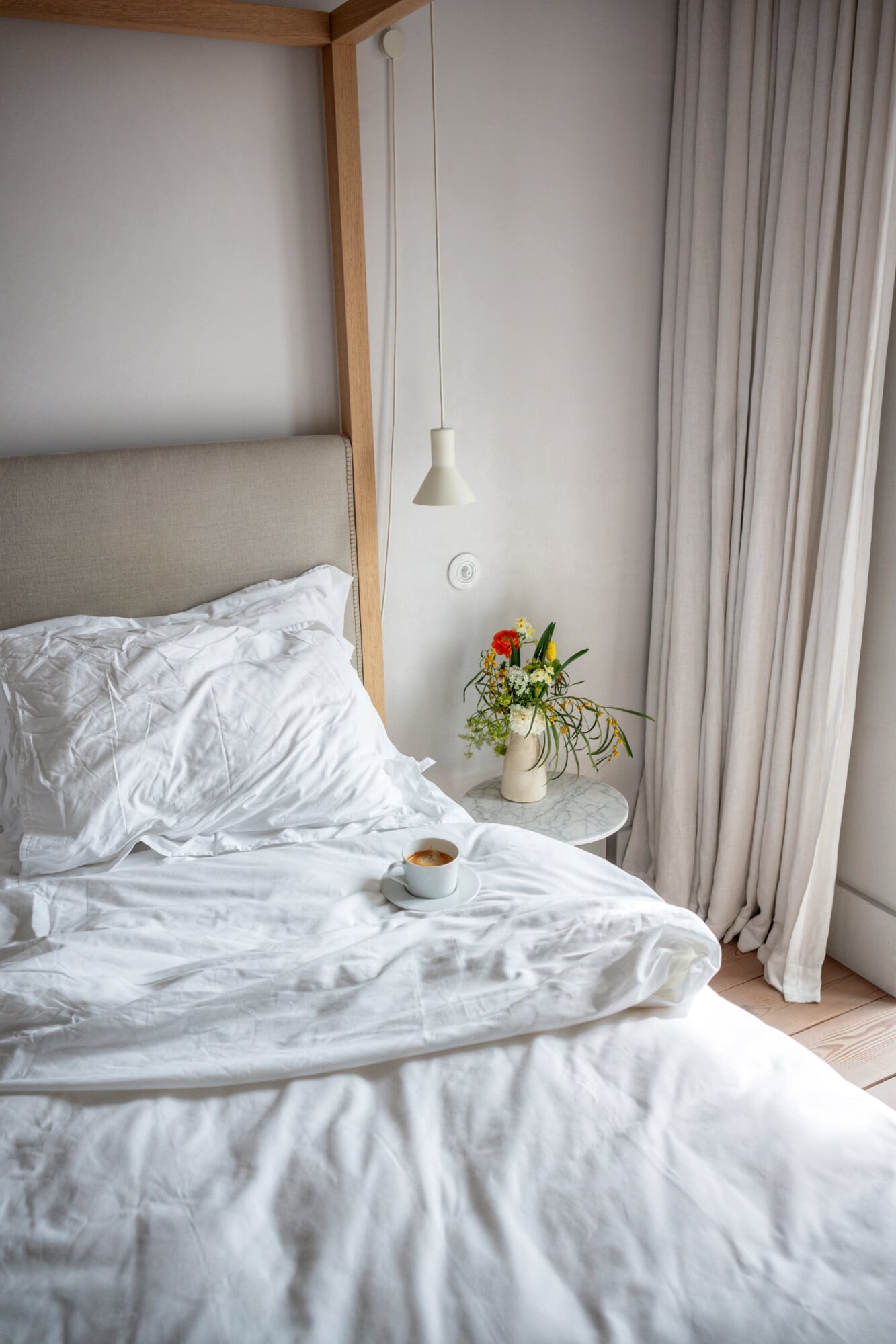 Santa Clara 1728, Portugal — Minimalist canopy bed with white linens, pendant light, fresh flowers in ceramic vase, and morning coffee on marble nightstand.