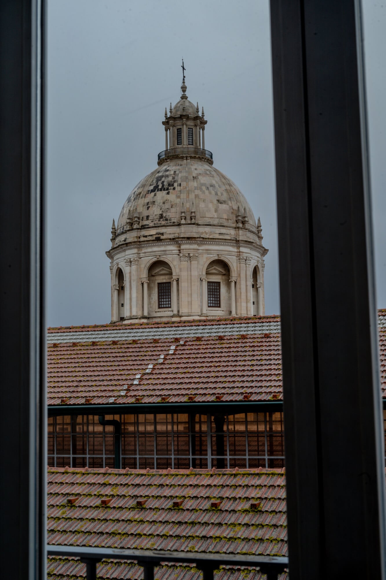 Santa Clara 1728, Portugal — Cream dome and lantern tower viewed through window frame with terracotta roofline, neoclassical architecture detail.