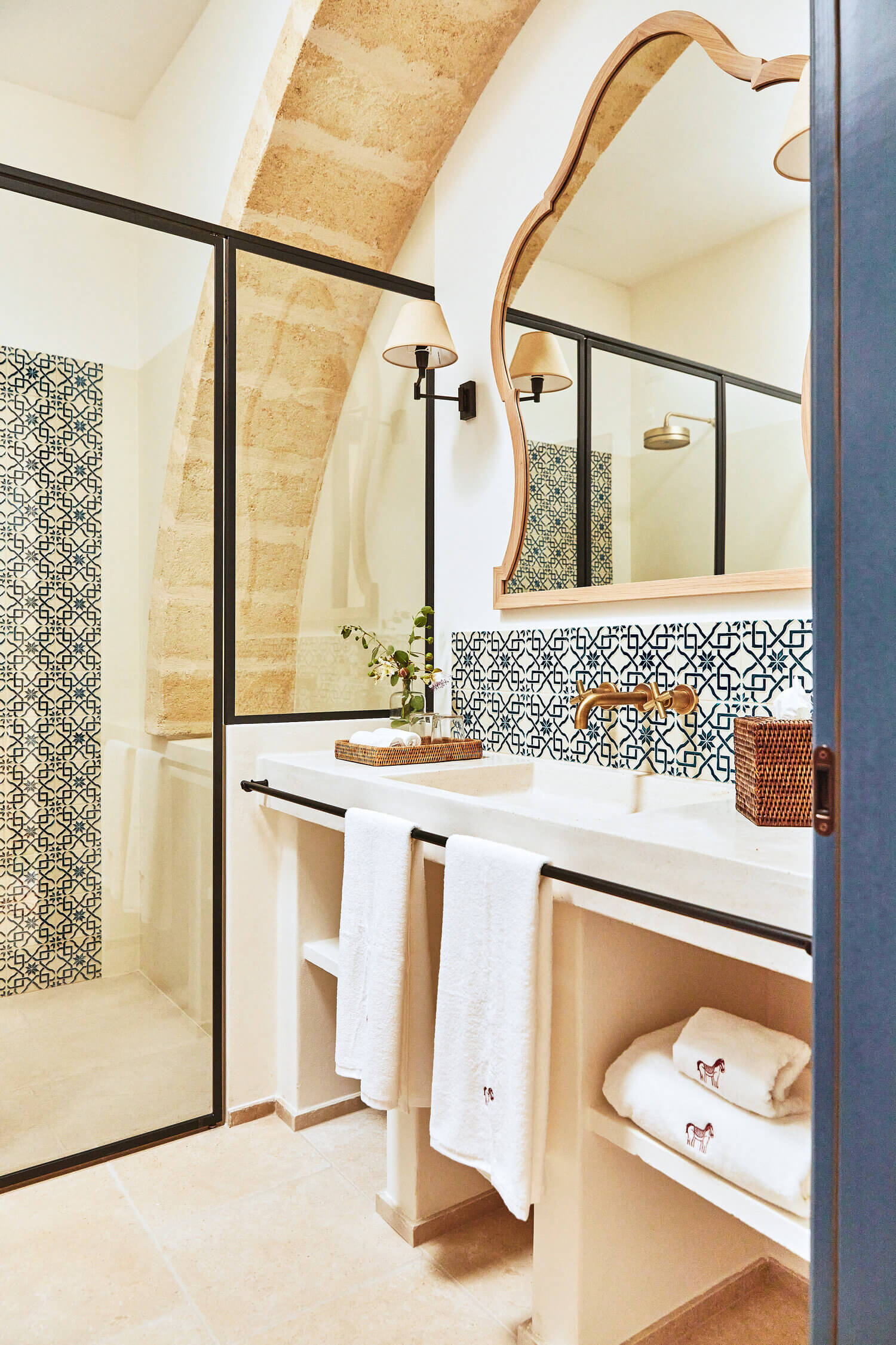 Masseria Calderisi, Europe — Spa bathroom with limestone archway, black-framed mirror, geometric tile backsplash, natural light, and minimalist coastal design.