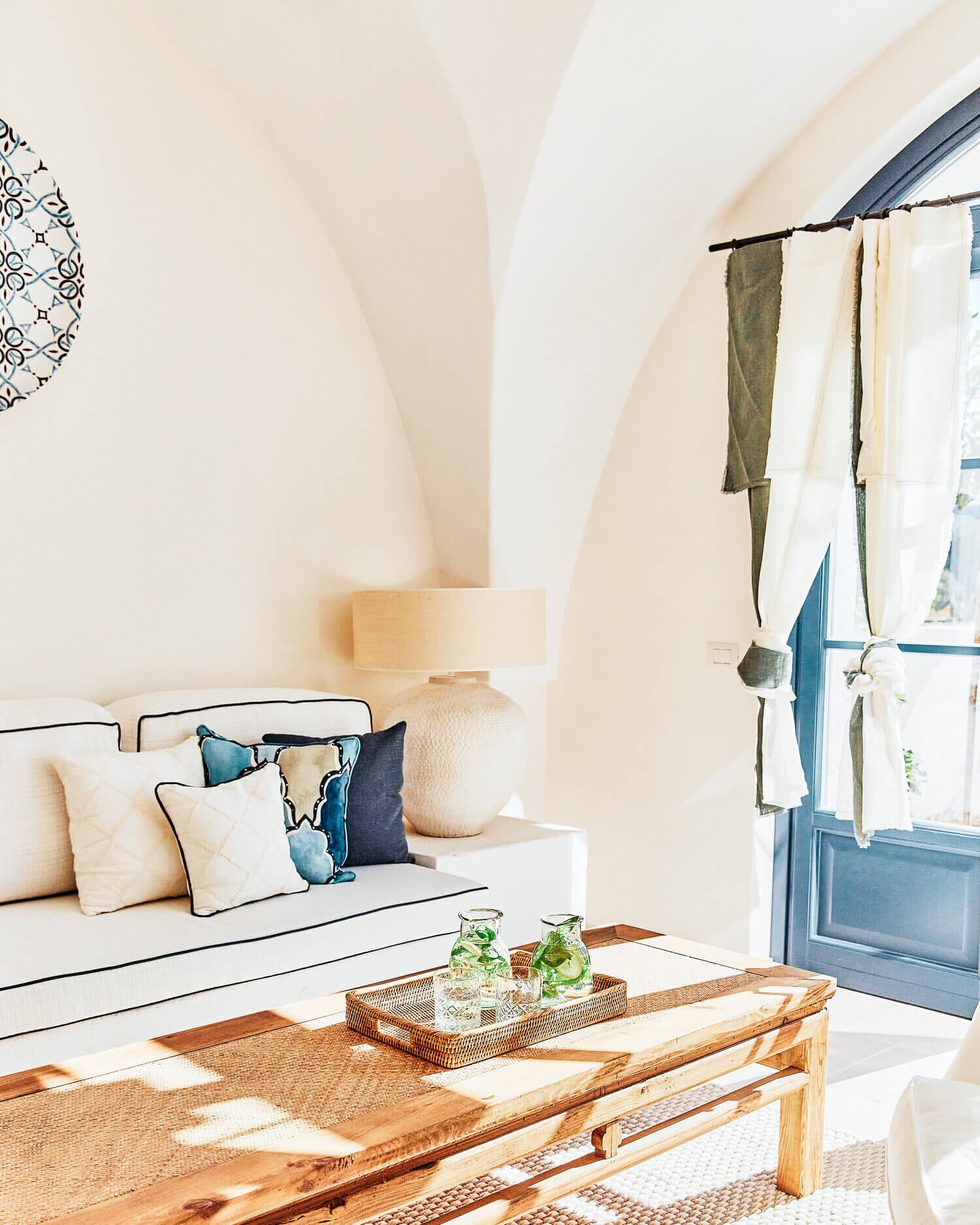 Masseria Calderisi, Europe — Whitewashed vaulted bedroom with arched ceilings, linen daybed, blue shuttered door, wooden table, natural light, Mediterranean minimalist design.