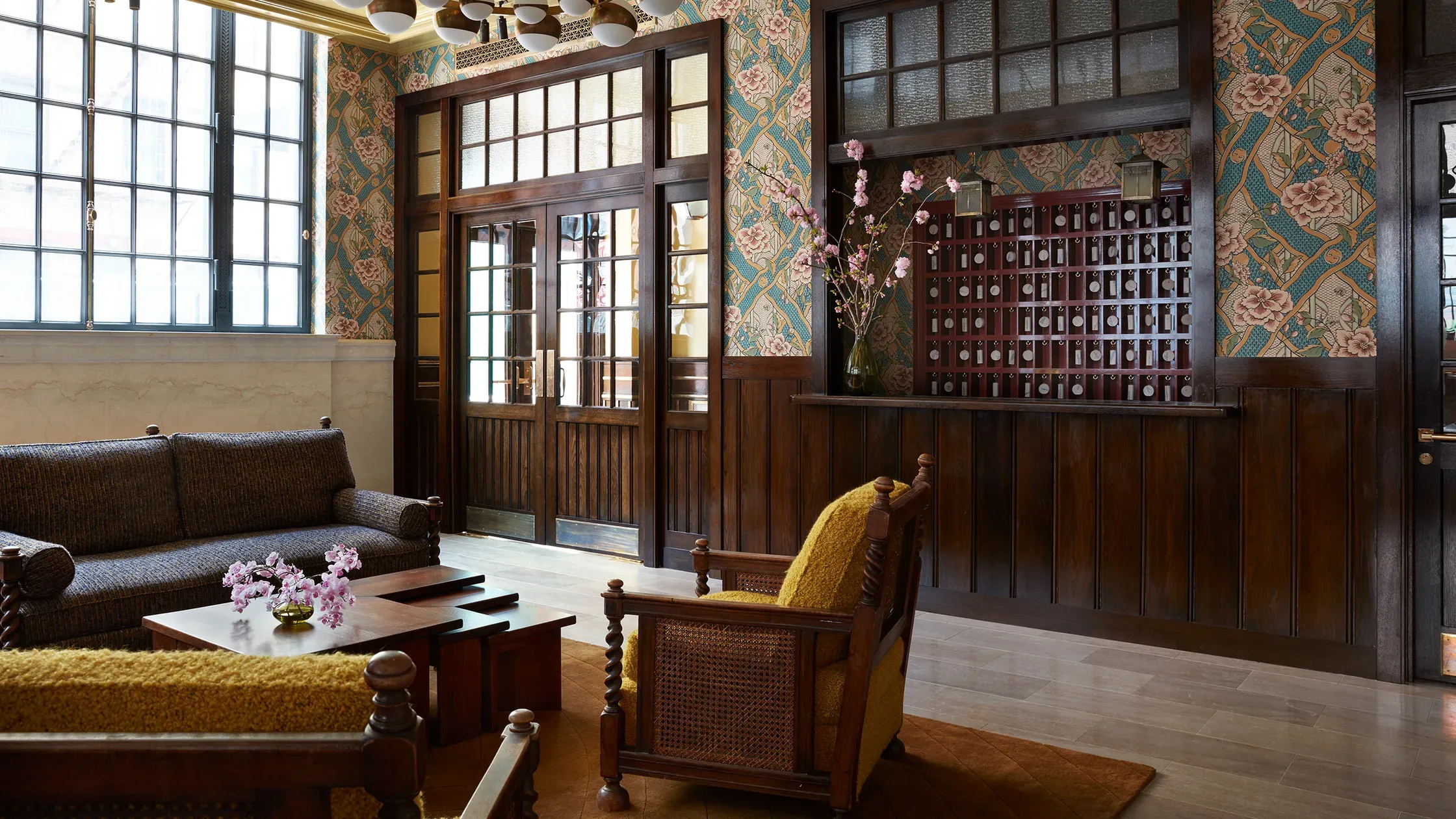 Nine Orchard, New York, USA — Dark wood paneling, patterned wallpaper, and vintage furnishings create an elegant gallery lounge with collected art displays and natural light.
