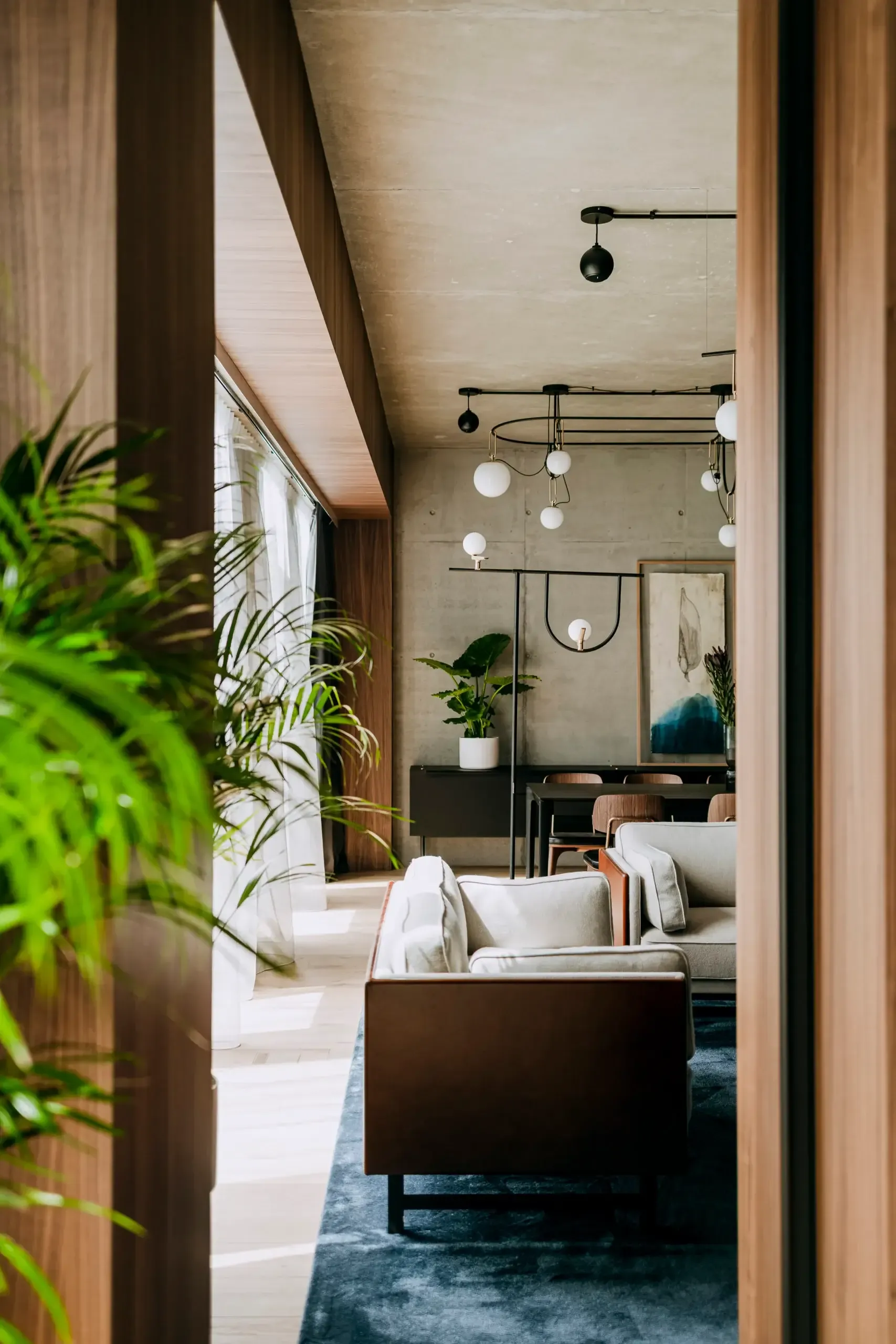 Nobu Warsaw, Poland — Modern hotel lobby with mid-century furniture, pendant lighting, concrete walls, natural light, potted plants, minimalist luxury interiors.