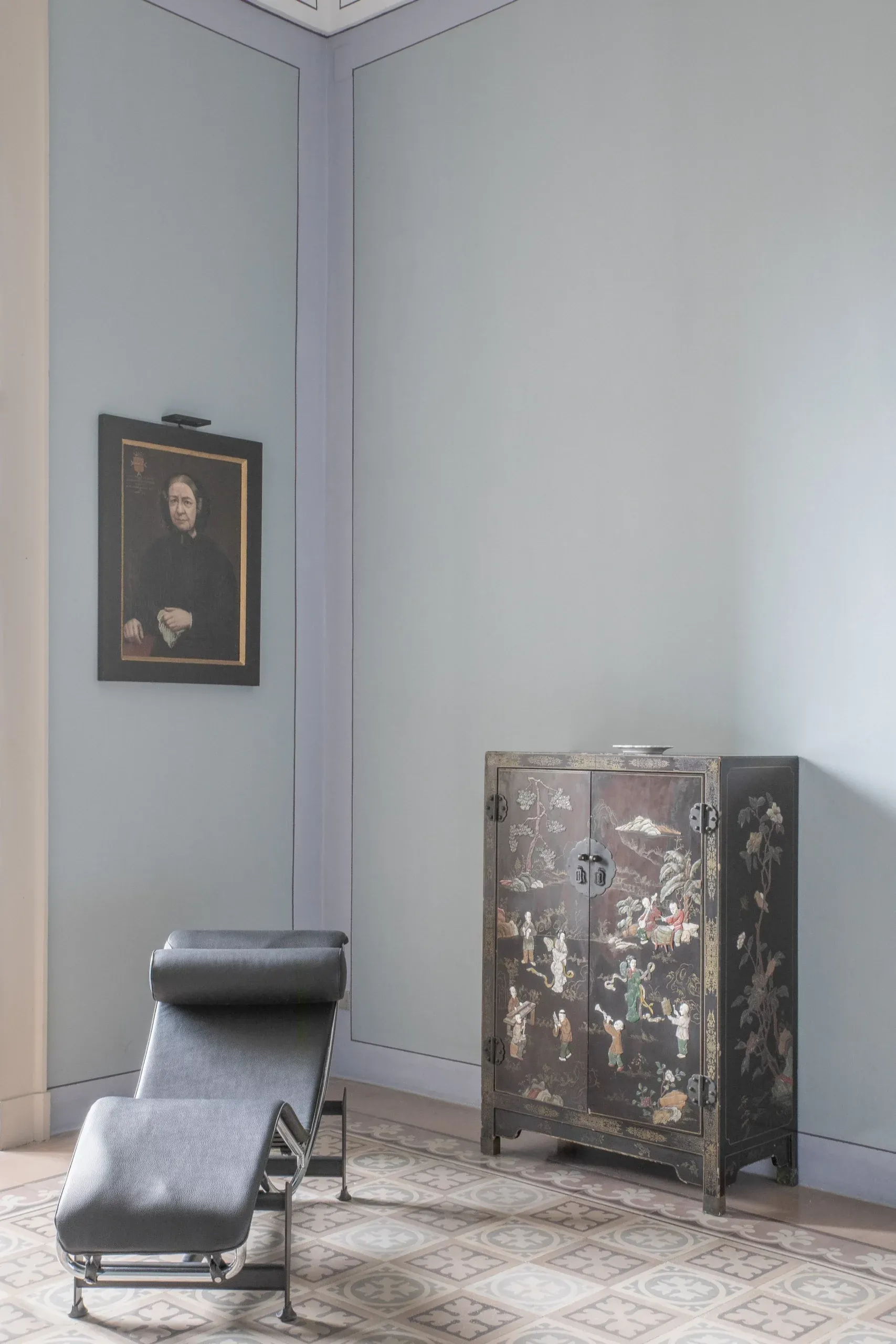 Palazzo Daniele, Europe — Minimalist corner gallery with portrait painting, lacquered chaise lounge, and ornate Asian cabinet on geometric floor tiles.