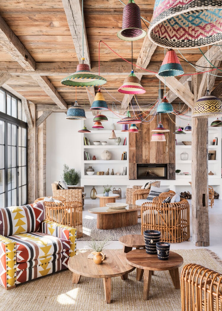 Quinta da Comporta, Europe — Woven pendant lights and patterned textiles suspended from timber beams above rattan seating and wooden tables in a bohemian-style lounge.