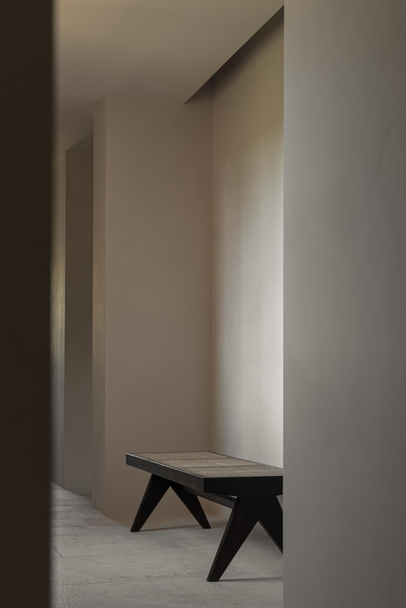 Can Gaspar, Balearic Islands, Spain — Minimalist corridor with angular black bench, soft natural light, whitewashed walls, concrete floor, contemporary architecture
