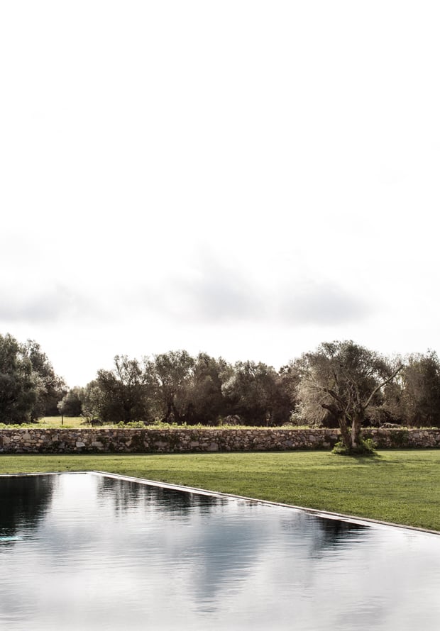 São Lourenço do Barrocal, Portugal — Reflective pool with manicured lawn, ancient olive trees, and stone wall under clouded sky.