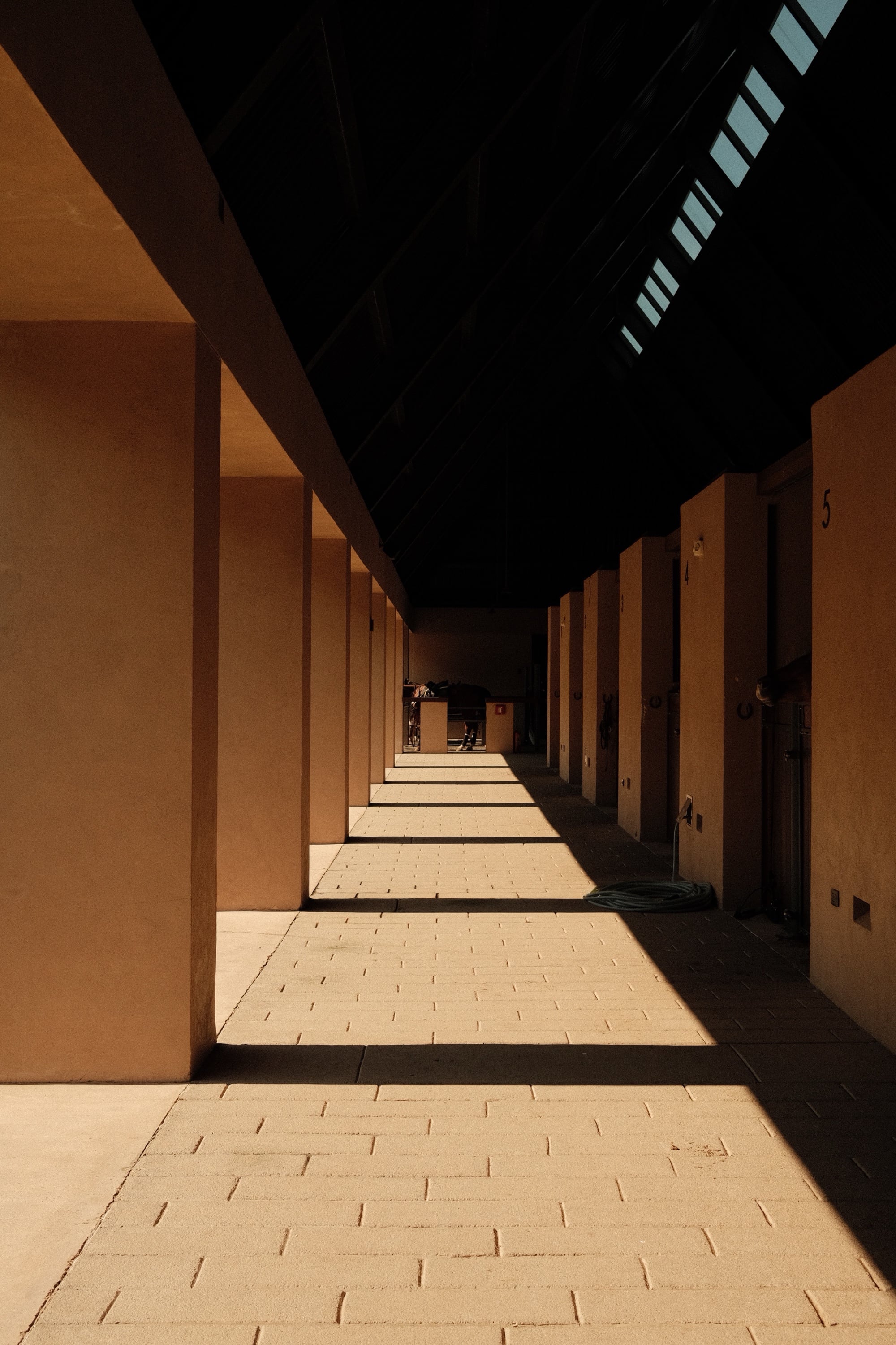 Rosewood Mandarina, Mexico — corridor of sunlit brickwork and raking shadow, photographed by KOBU