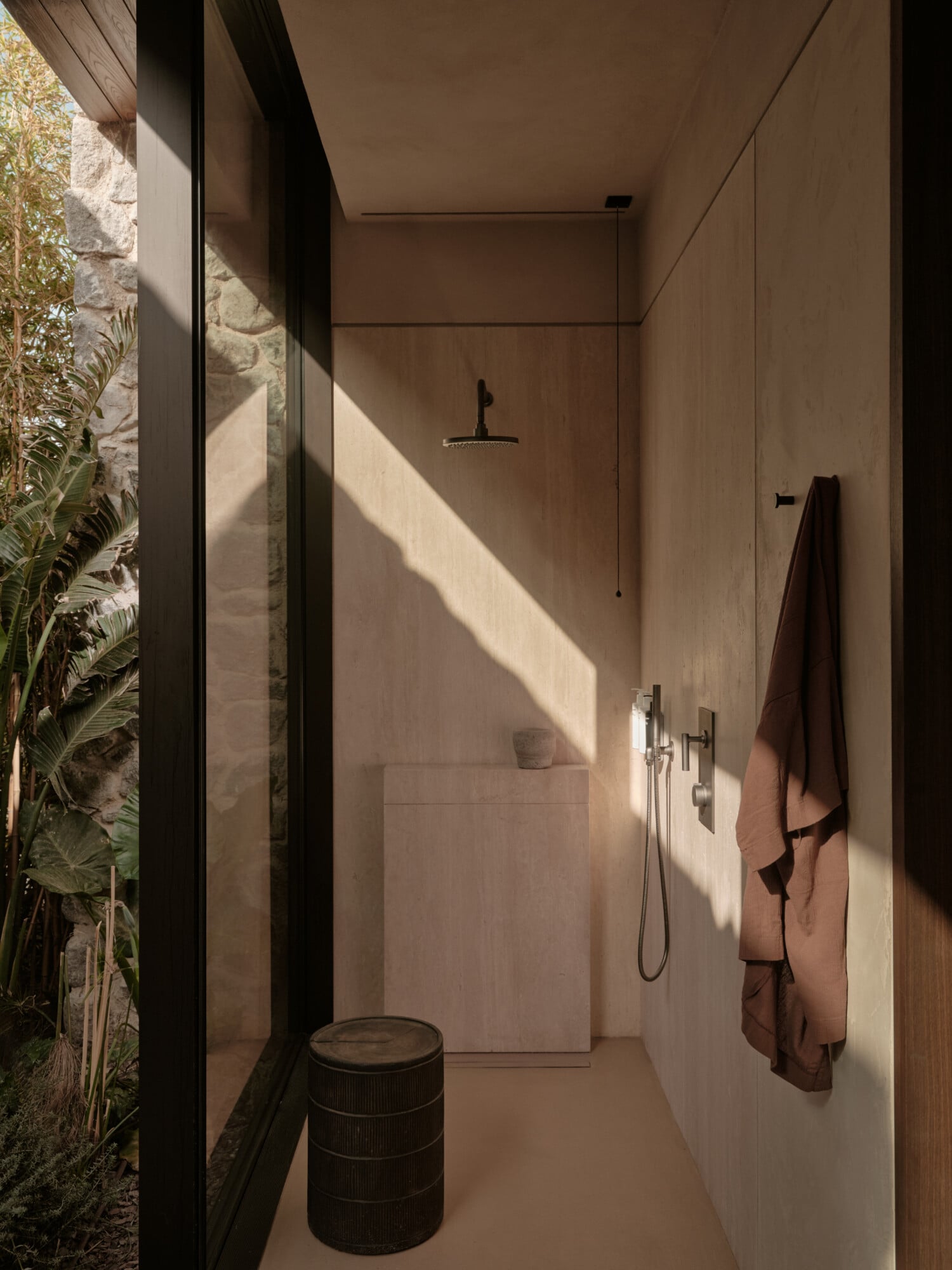 Scorpios Bodrum, Mediterranean — Outdoor shower with stone walls, overhead rainfall showerhead, and natural light streaming across minimal interior space.