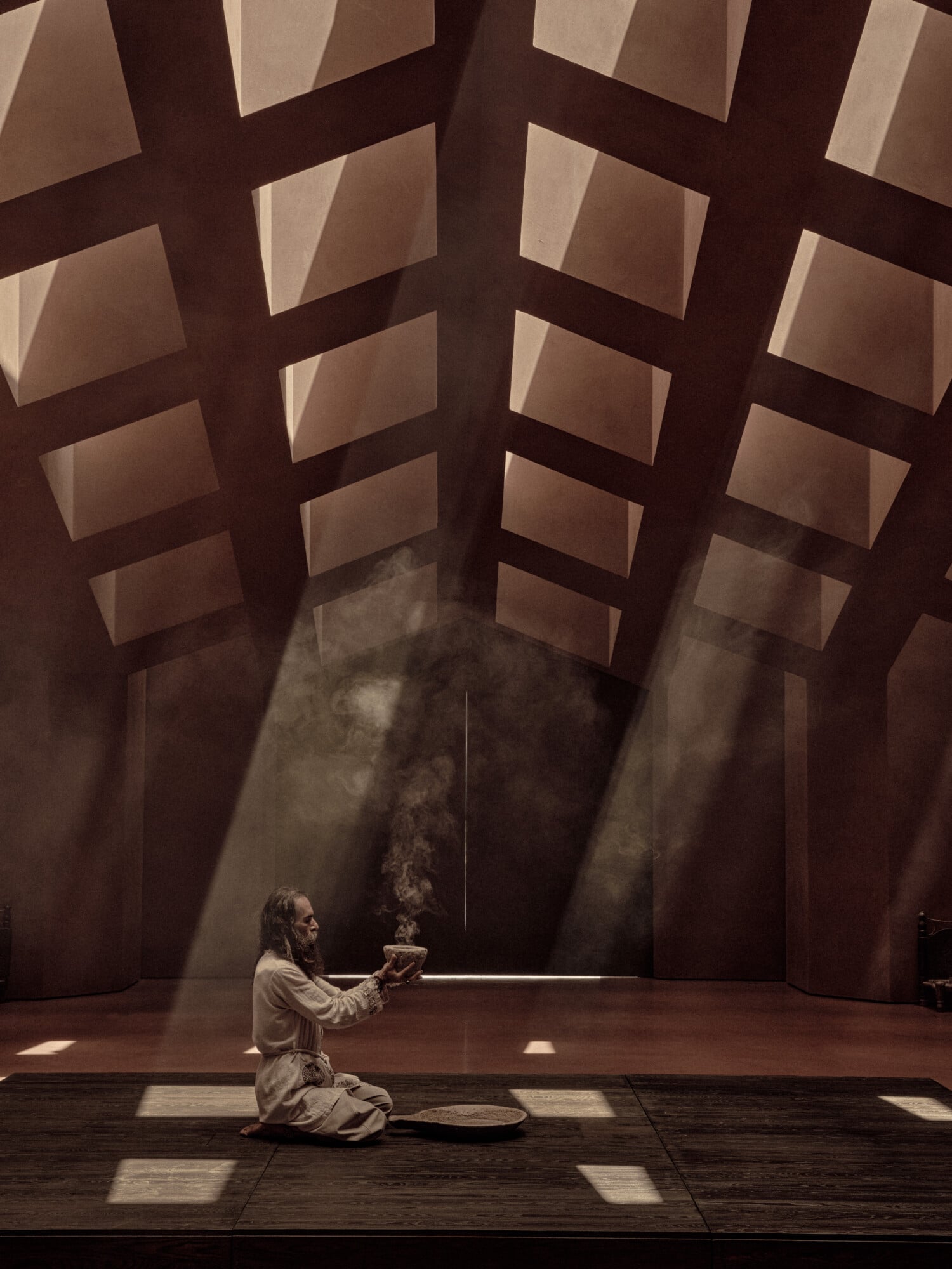 The Ritual Space, Mediterranean — Person kneeling in contemplation within brutalist concrete chapel, dramatic skylights casting geometric shadows across ochre walls.