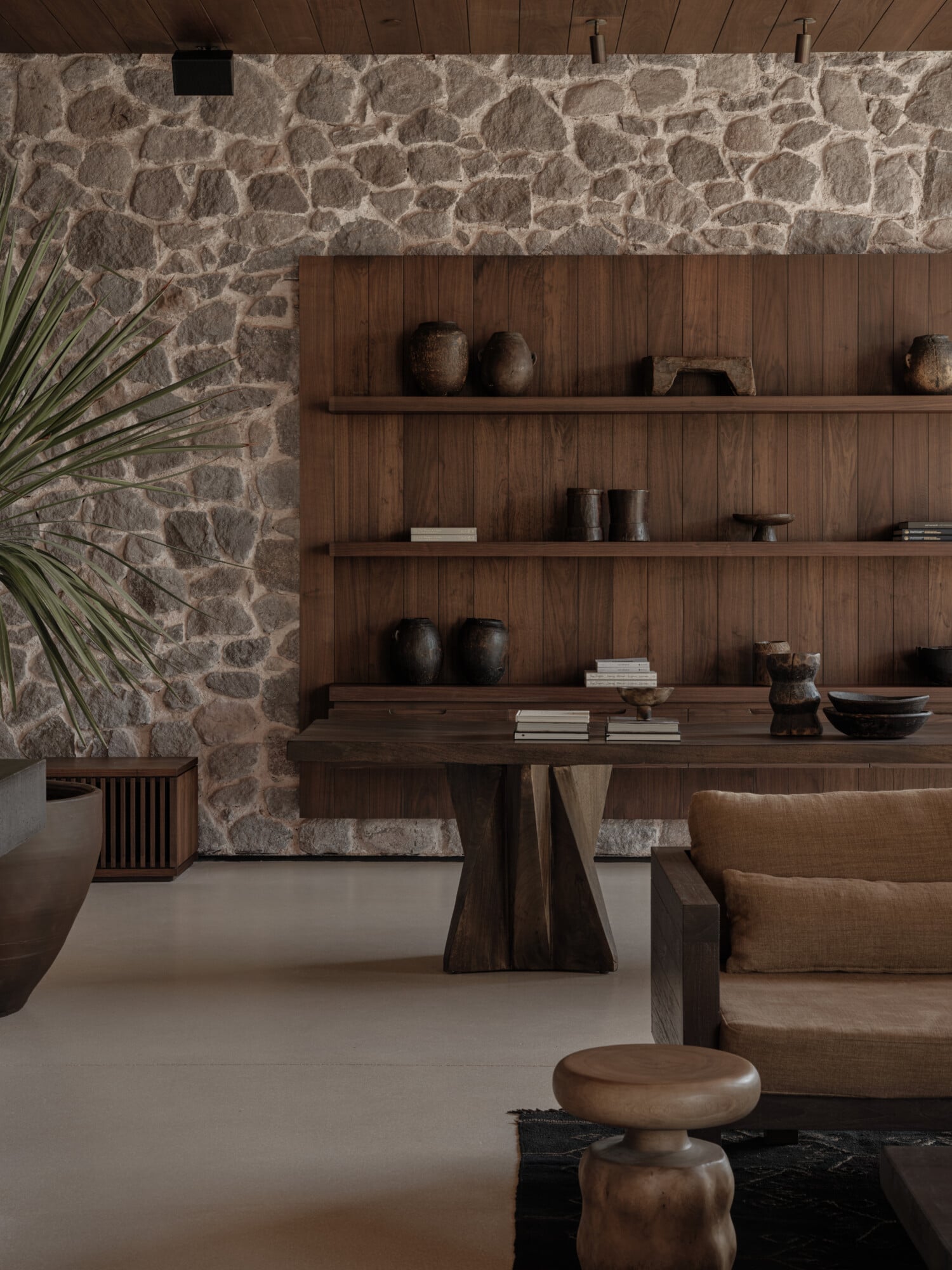 Scorpios Bodrum, Mediterranean — Stone accent wall with dark wood shelving, ceramic vessels, and natural light in minimalist luxury interior design space.