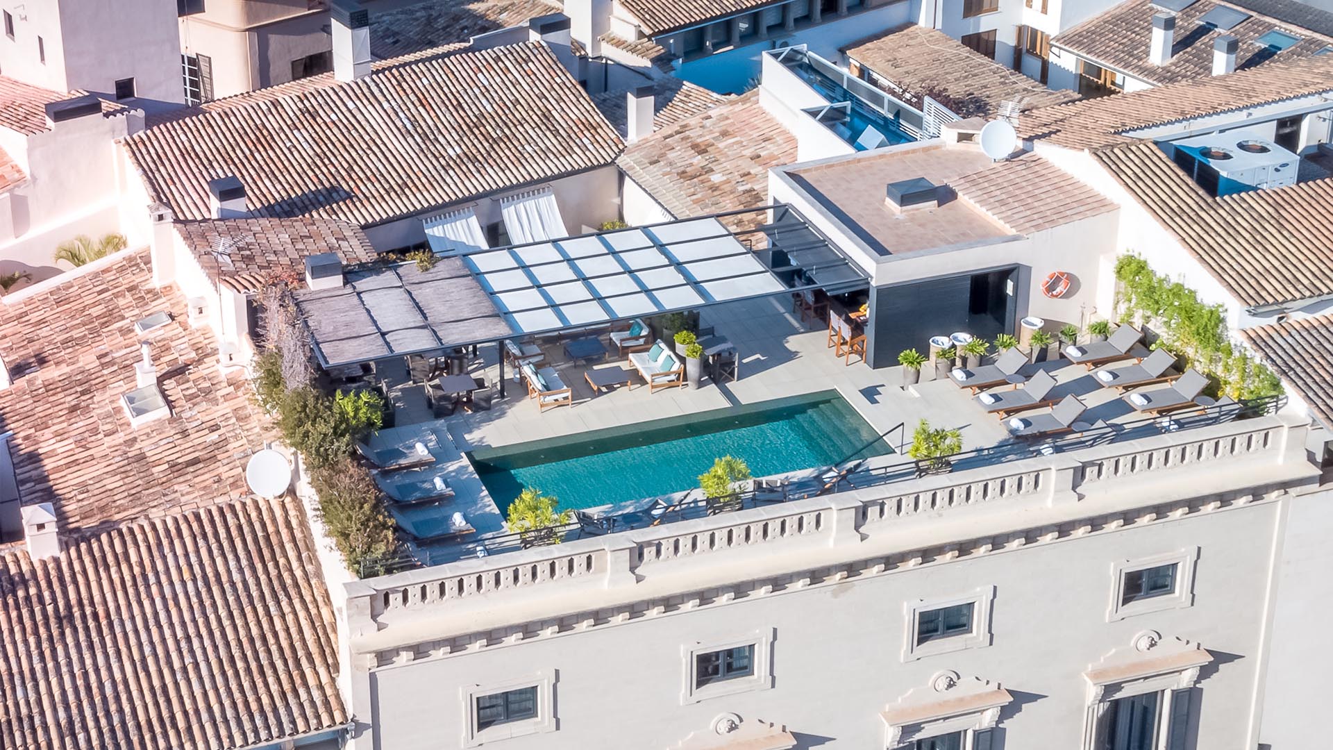 Sant Francesc Hotel Singular, Balearic Islands, Spain — Rooftop terrace with turquoise pool, modern pergola, loungers, and Mediterranean architecture in afternoon light.