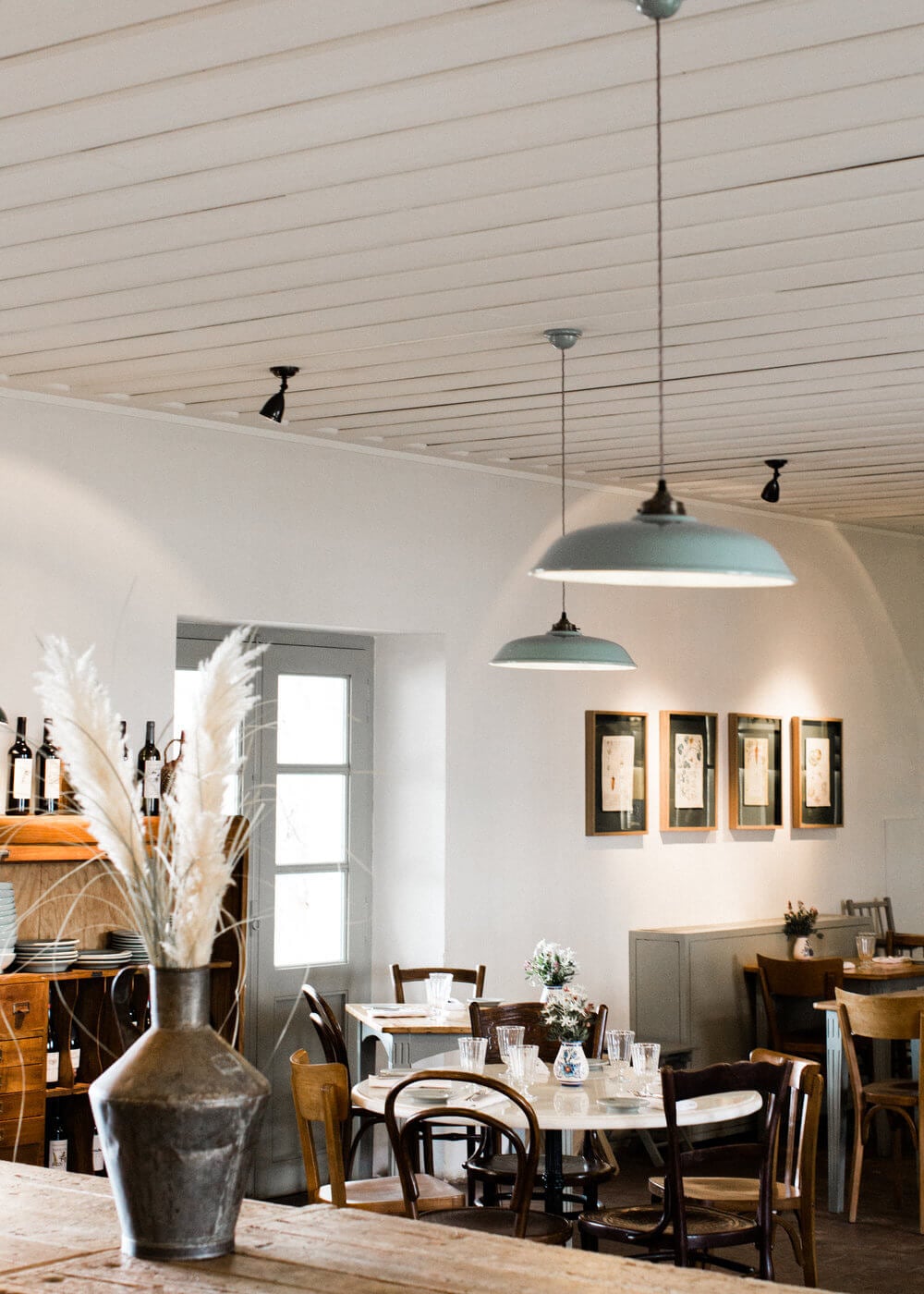 São Lourenço do Barrocal, Portugal — Dining room with vaulted ceiling, pendant lights, wooden chairs, stone vessels, and framed artwork above sideboard.