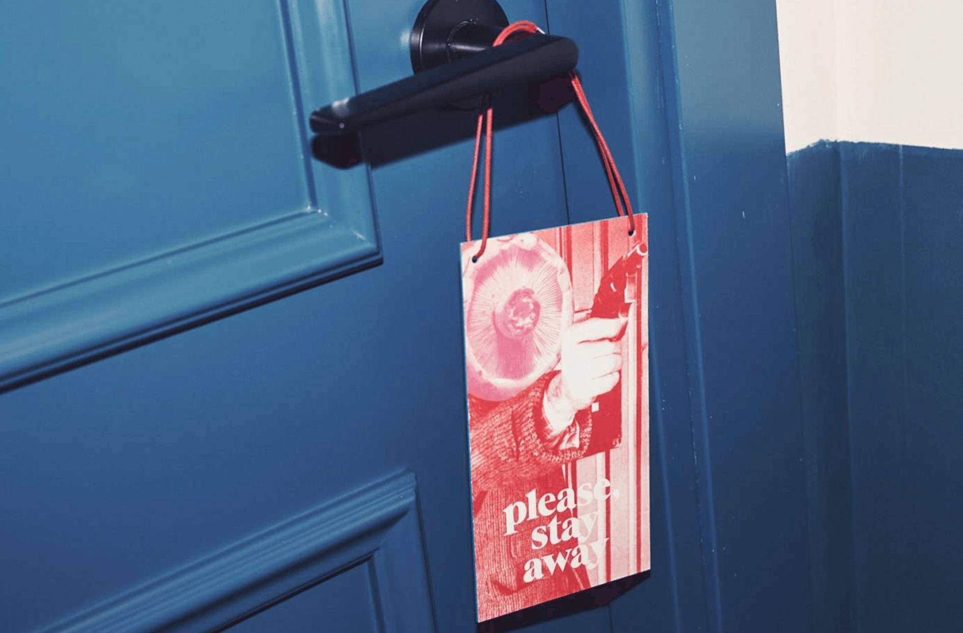 Casa Bonay, Europe — Red and white do not disturb door hanger suspended from black hardware against blue painted door and mountain landscape.