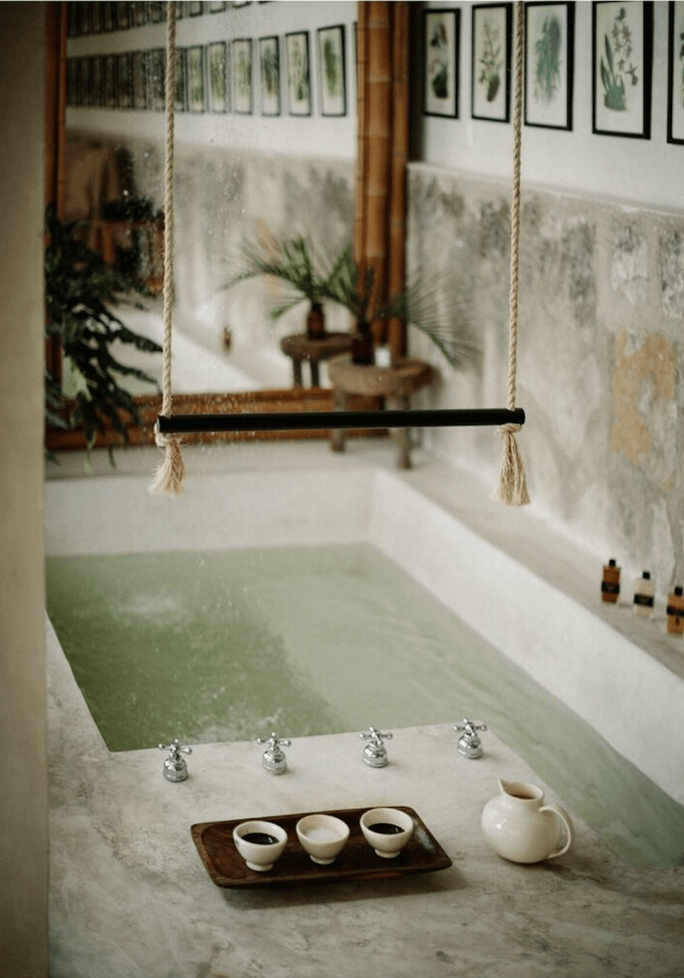 Coqui Coqui Spa, Mexico — Minimalist marble bathtub with suspended rope swing, ceramic vessels, and botanical prints in serene spa bathroom.