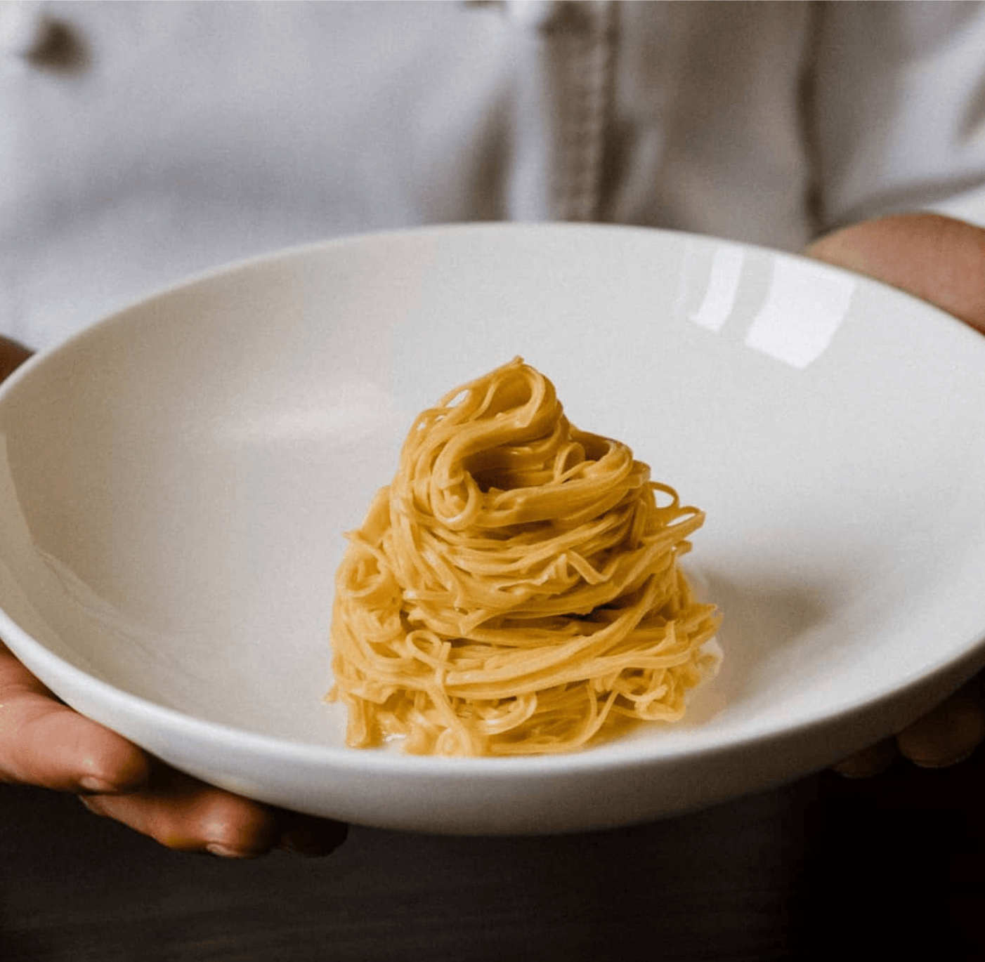 Casa di Langa, Europe — Single portion of golden spaghetti nest arranged on white ceramic plate, minimalist fine dining presentation with soft natural light.