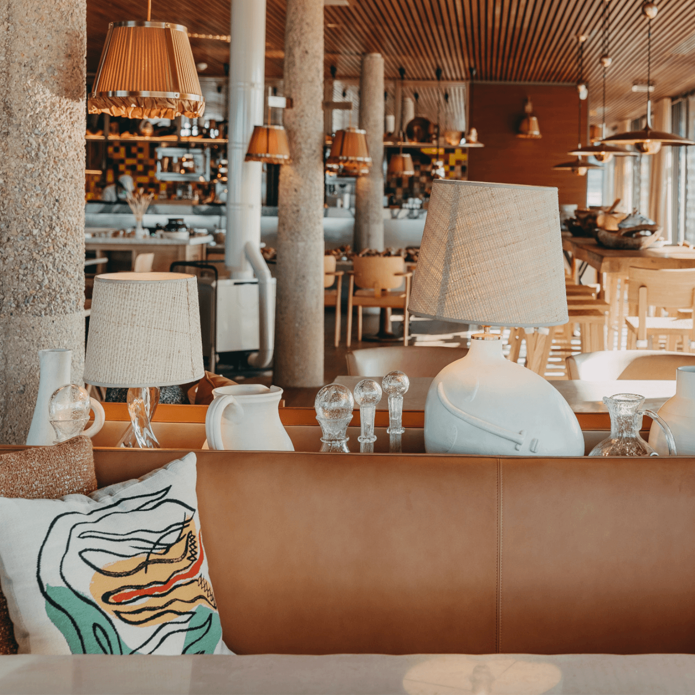 Lily of the Valley, Europe — Modern hotel lobby with cognac leather seating, linen lampshades, terrazzo accents, and sculptural white ceramics in warm natural light.