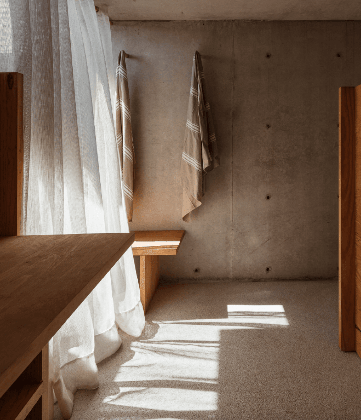 Hotel Terrestre, Mexico — Minimalist concrete bathroom with natural light, wooden fixtures, linen textiles, and brutalist architecture.