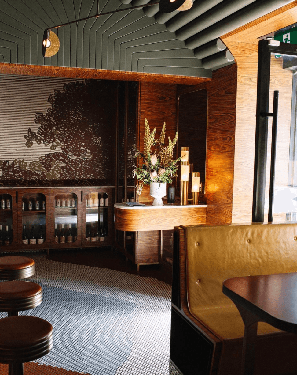 Aloette Restaurant, North America — Art deco bar interior with walnut wood paneling, geometric ceiling details, brass accents, and leather banquette seating.