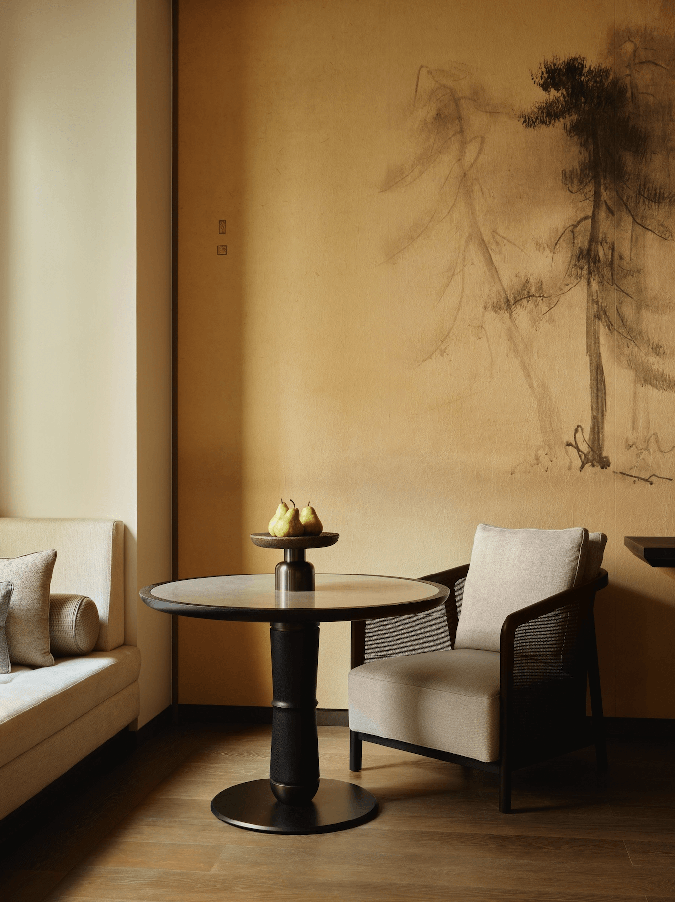 Aman New York, New York, United States — Minimalist lounge with ink-wash mural, black pedestal table, cream linen seating, and natural light on warm terrazzo floor.