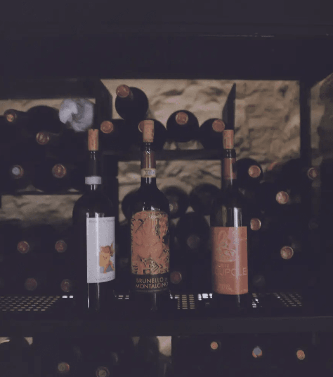 Master Sommelier Wine Tastings, Europe — Three wine bottles with cork-sealed wooden crates stacked in candlelit cellar ambiance, warm lighting on dark stone archway backdrop.