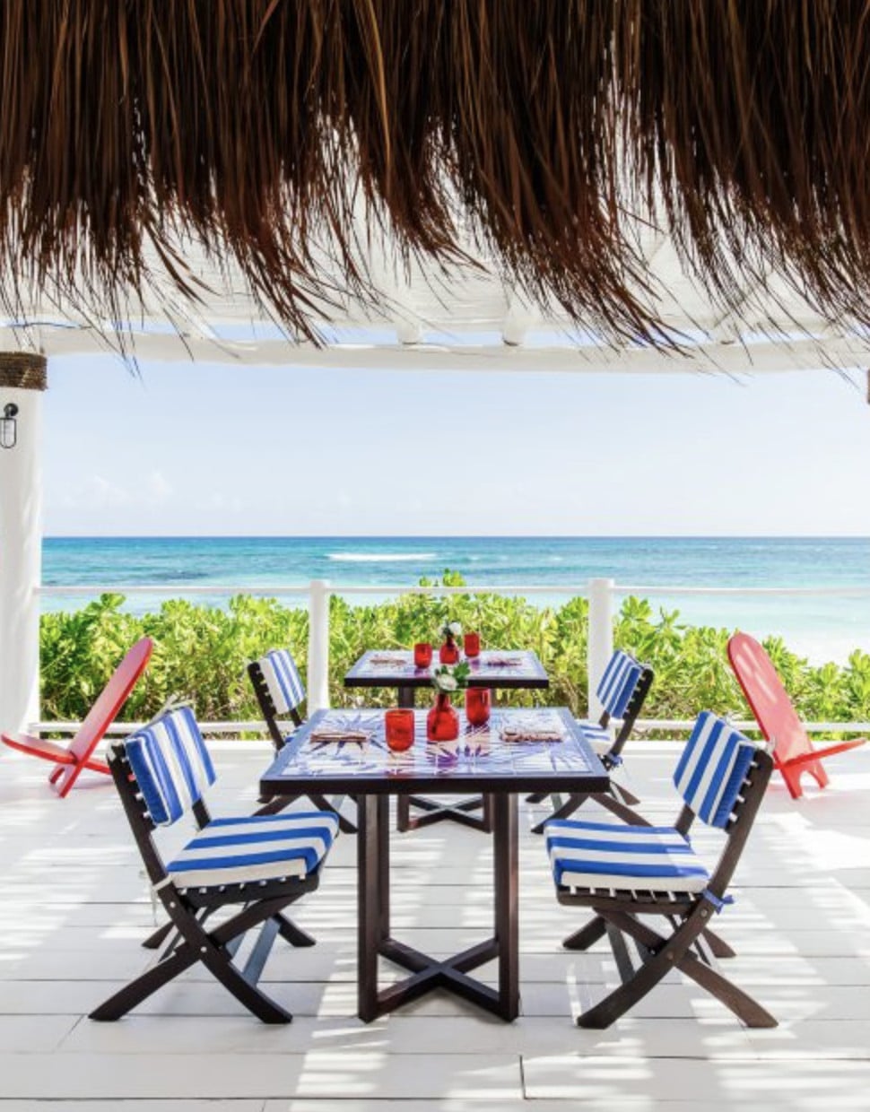 Mistura, Mexico — Beachfront dining terrace with striped blue chairs, thatched palapa roof, and turquoise ocean views beyond native vegetation.