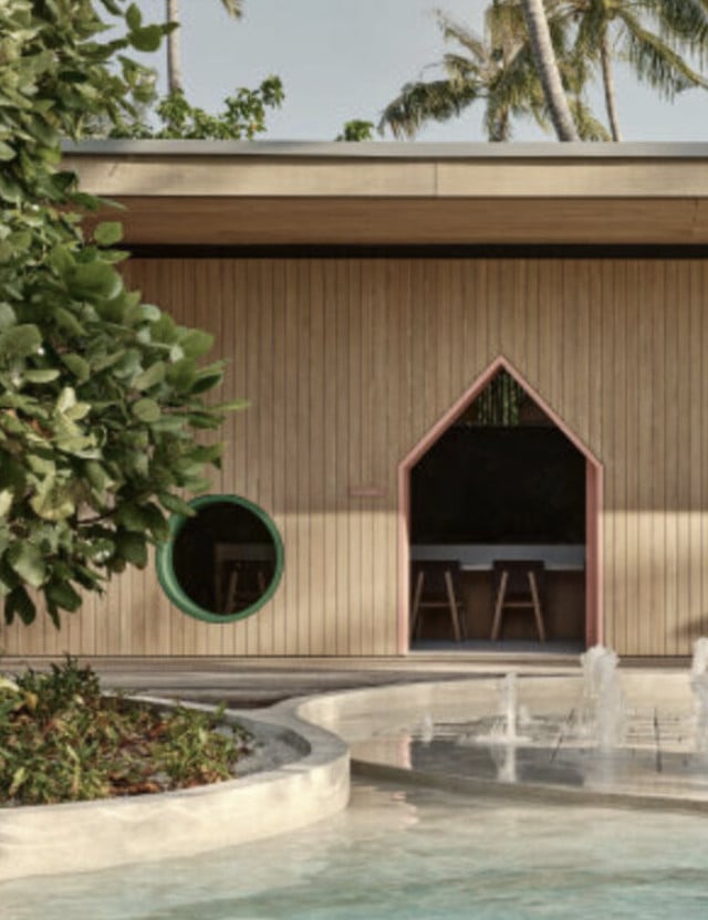 Fab Lab, Asia — Corrugated metal pavilion with arched openings, curved concrete terrace, and tropical landscaping in warm sunlight.
