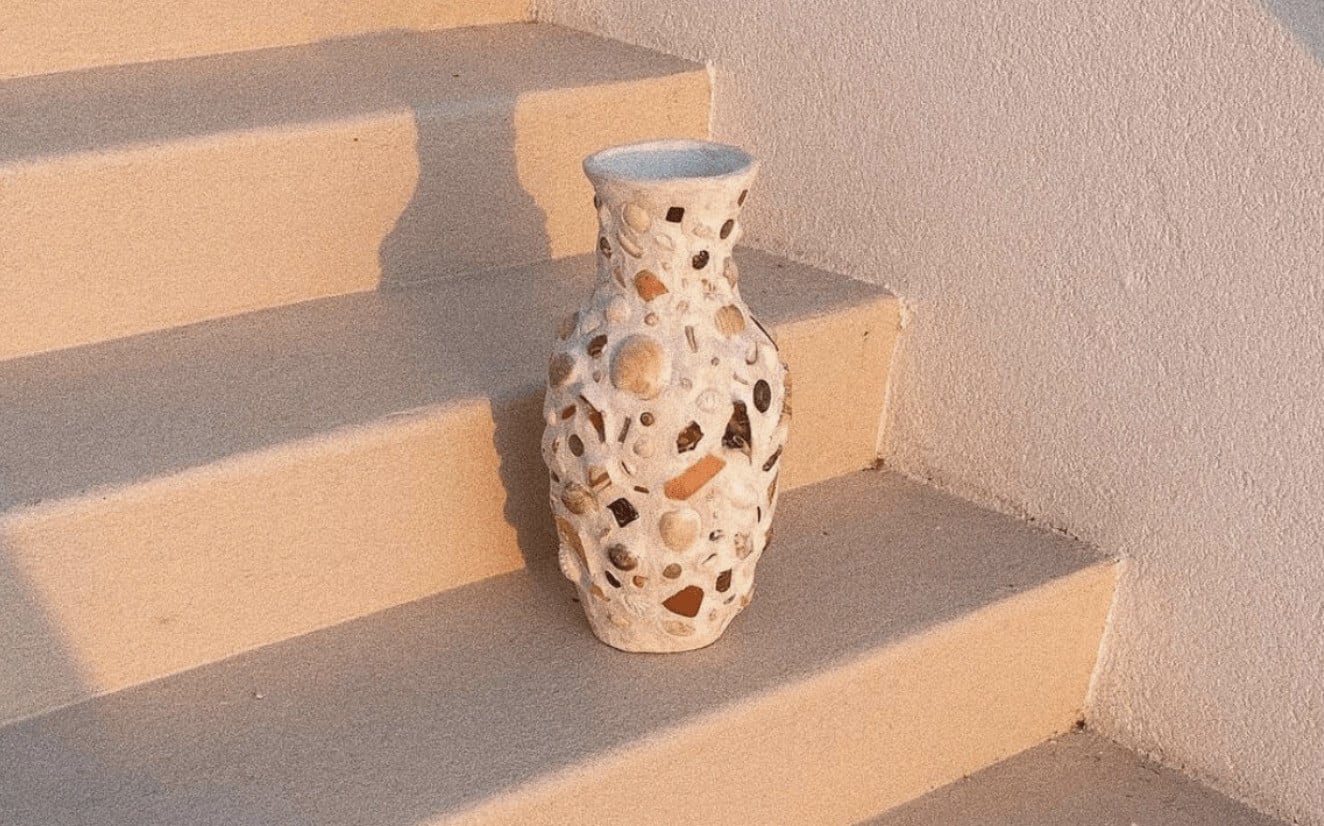 Art Residency  — Terrazzo vase with blue rim on sunlit concrete steps, casting geometric shadows in minimalist architectural setting.