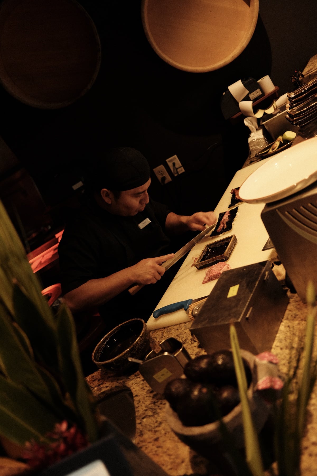 Chef plating a dish with precision at Agave Azul, warm kitchen light casting shadows across the prep station.