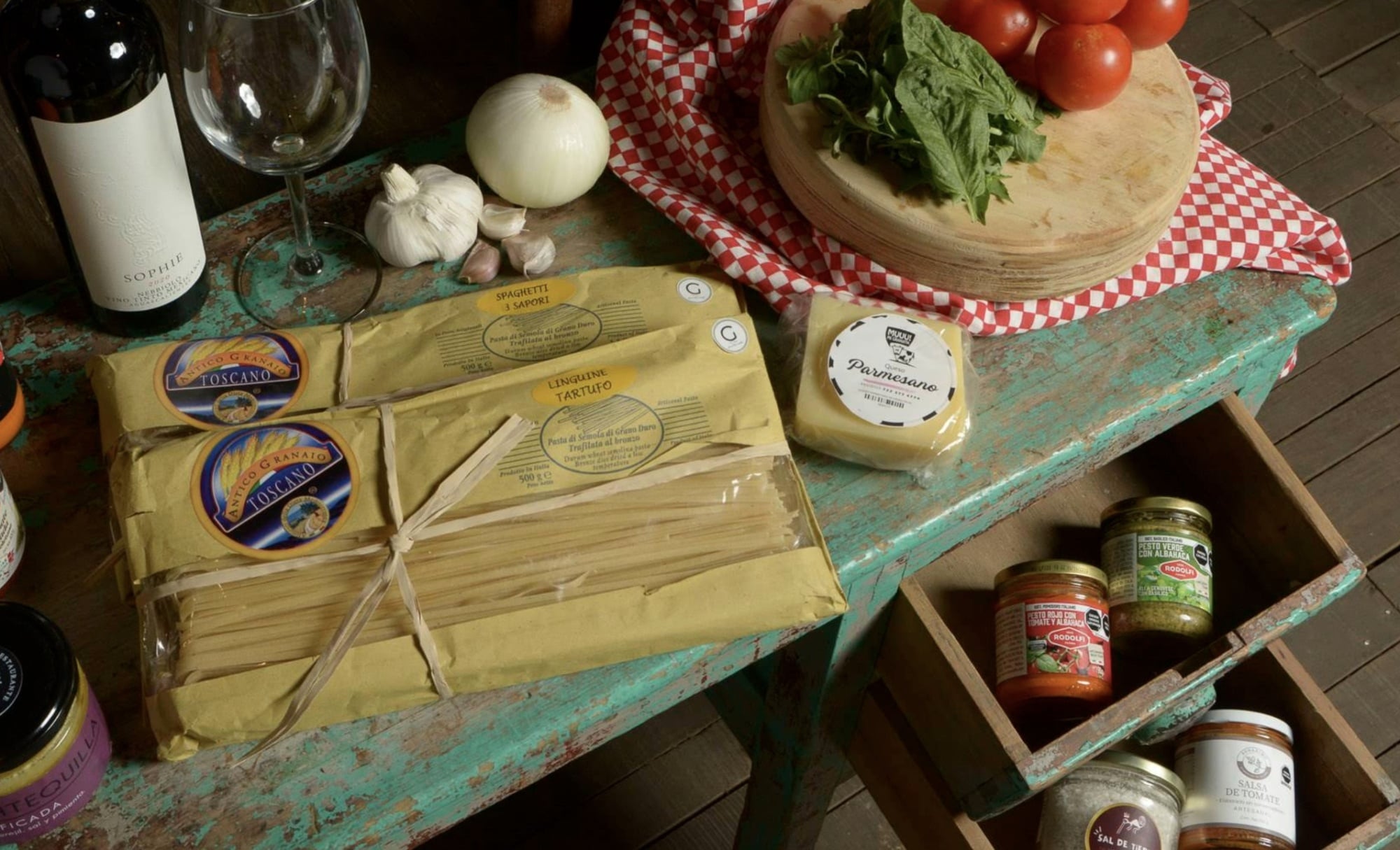 Mercado Gourmet/Restaurante San Ramón — Mercado Gourmet, Mexico — Italian pantry staples arranged on distressed turquoise wood with fresh herbs, tomatoes, wine, and artisanal cheeses in rustic culinary styling.