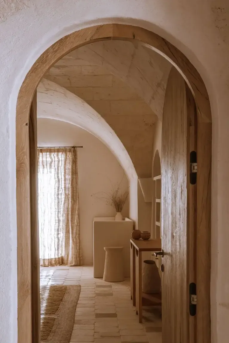 Son Blanc Farmhouse, Balearic Islands, Spain — Arched wooden doorway with natural light filtering through linen curtains into minimalist Mediterranean interior.