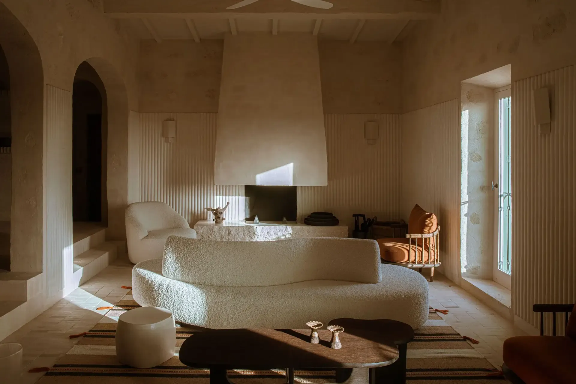 Son Blanc Farmhouse, Balearic Islands — Minimalist living room with curved cream boucle sofa, arched doorways, terracotta tile floors, natural light, Mediterranean luxury interior design.