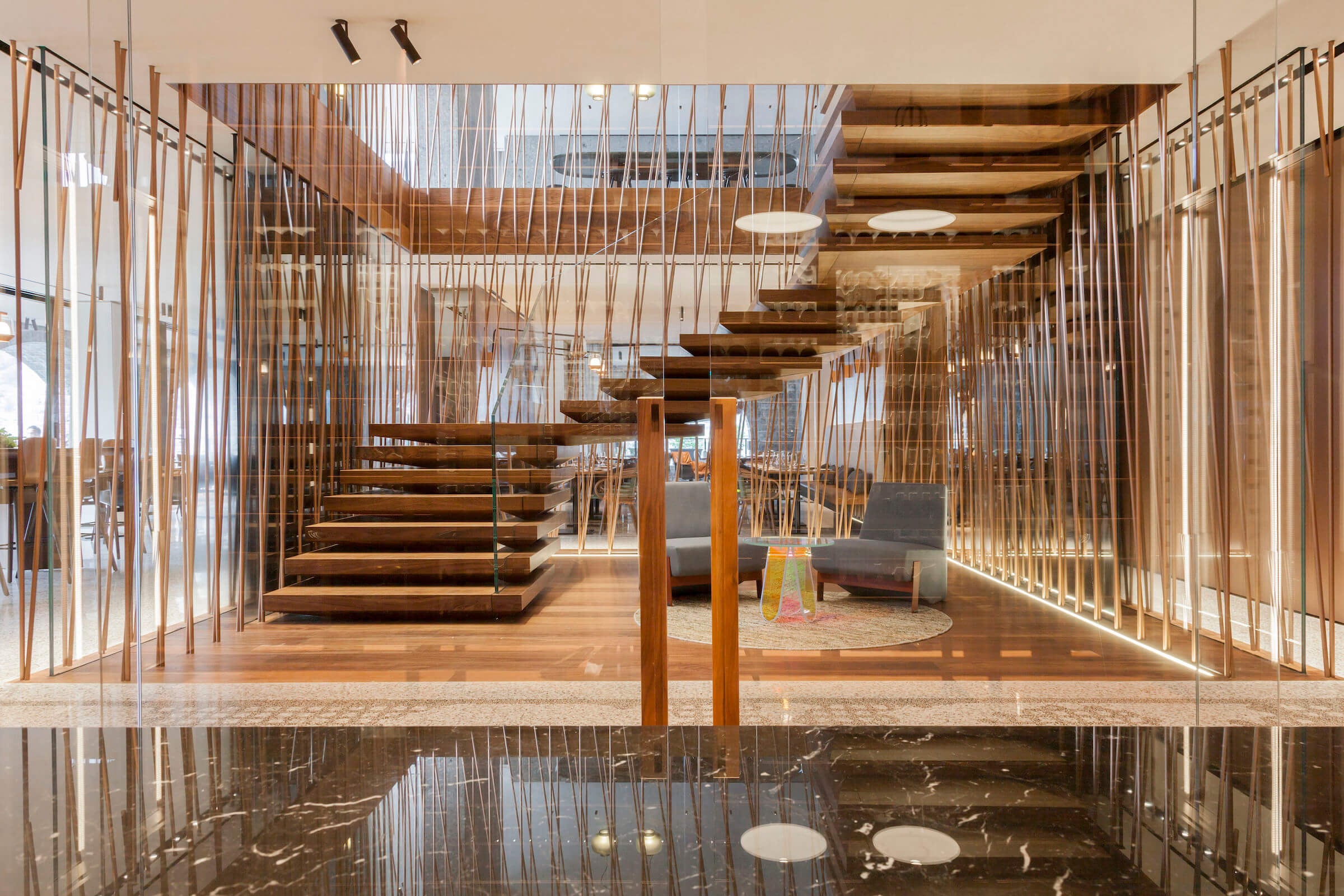 il Sereno Lago di Como, Europe — Floating timber staircase with brass railings, vertical wood-slat partitions, and natural light flooding through skylights in minimalist luxury interior.