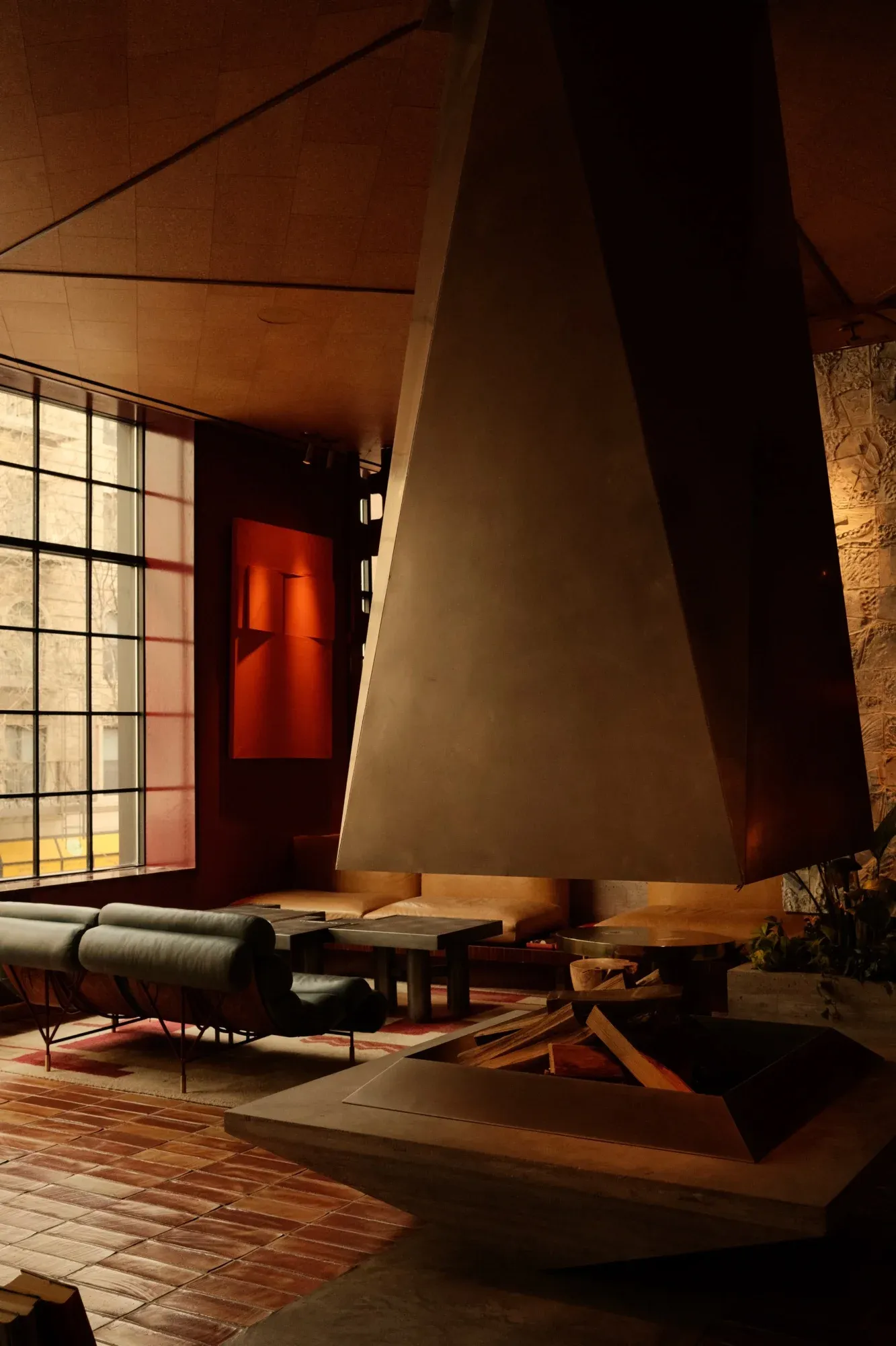 The Manner, New York — fireplace lounge with sculptural metal hood in evening light, photographed by KOBU