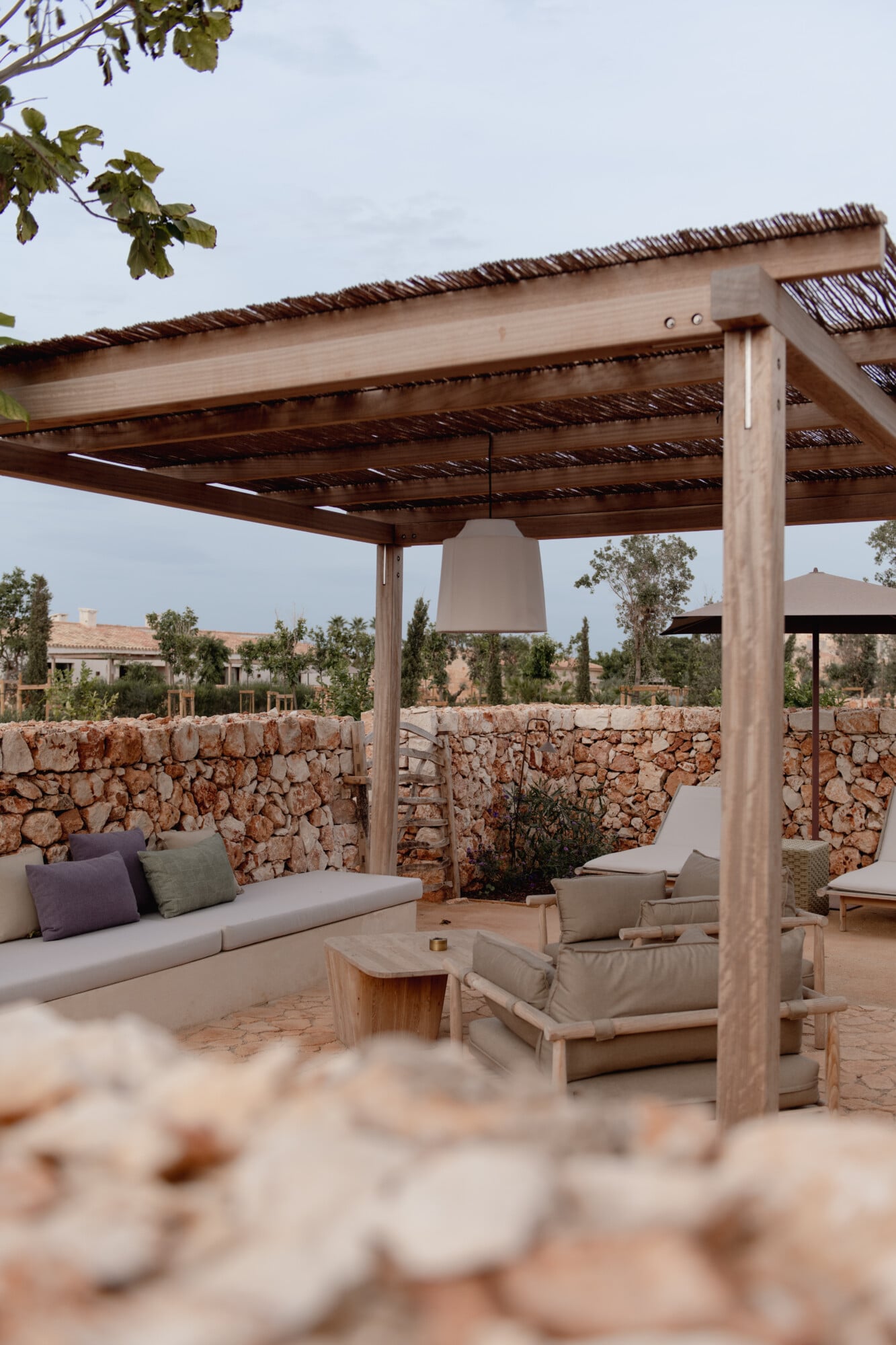 Son Vell, Balearic Islands — Wooden pergola with woven roof detail shading stone terrace seating area overlooking rural landscape.
