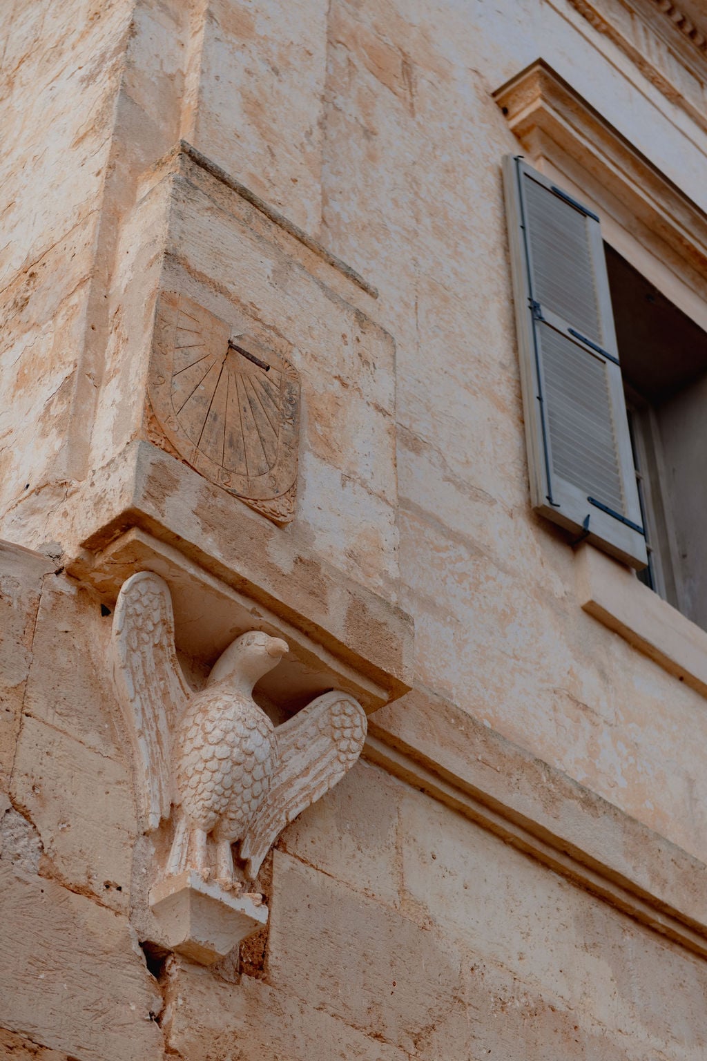 Stone facade detail with carved eagle corbel and sundial, Son Vell, Balearic Islands.