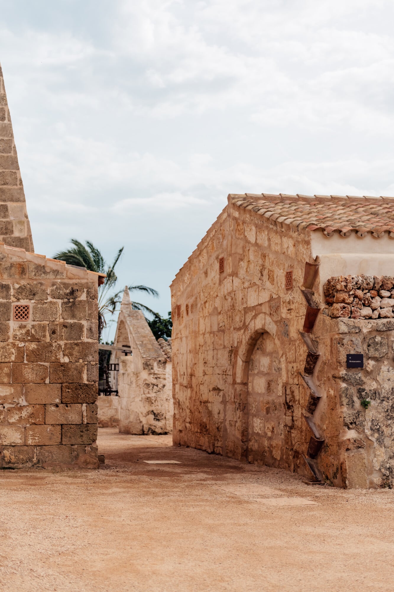 Son Vell, Balearic Islands — Terracotta stone archways and weathered masonry passages with terra cotta roof tiles, Mediterranean vernacular architecture.