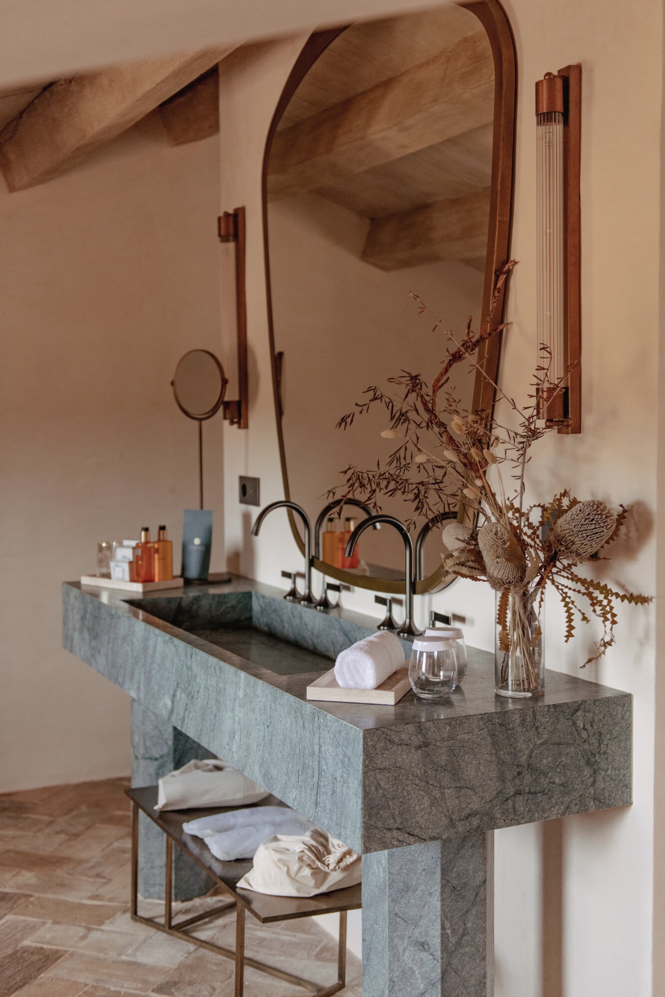 Son Vell, Balearic Islands — Minimalist bathroom with dual stone sink, arched mirrors, dried botanicals, and warm neutral palette.