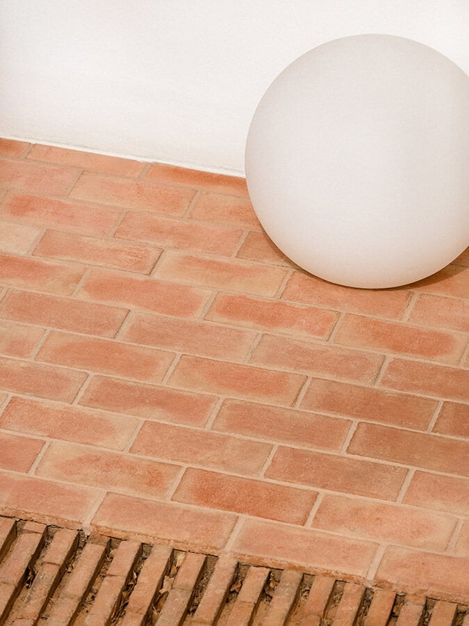 Casa Modesta, Europe — Minimalist interior detail with cream sphere against terracotta brick wall and white ceiling, clean modernist aesthetic.