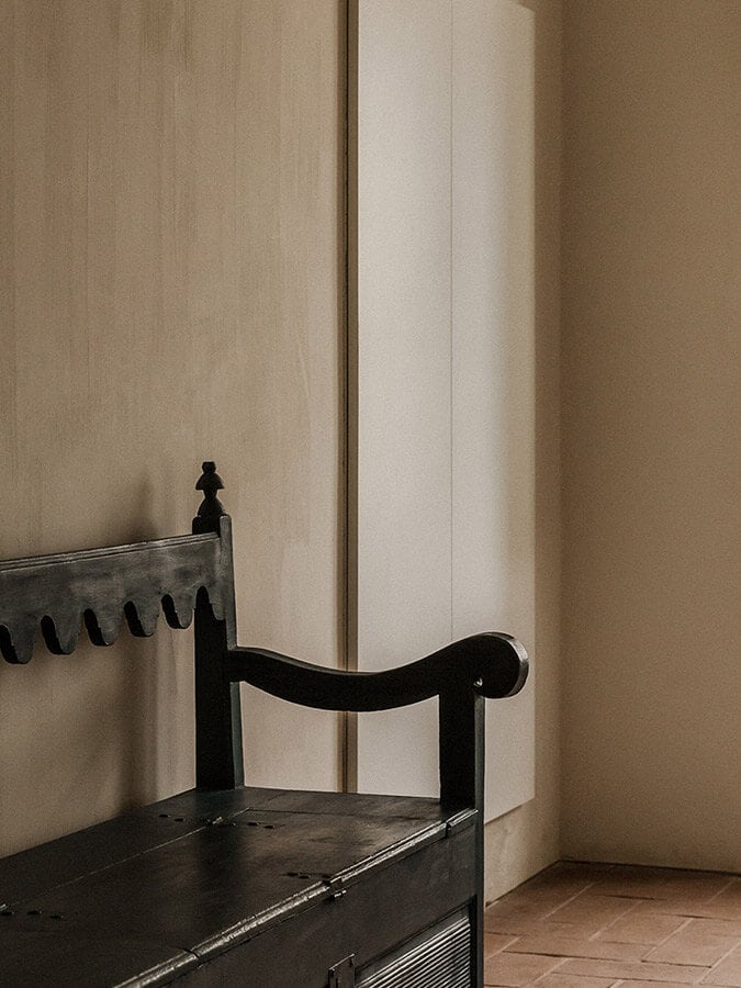 São Lourenço do Barrocal, Portugal — Black wooden chair against cream textured walls and terracotta floor, minimalist architectural detail with soft natural light