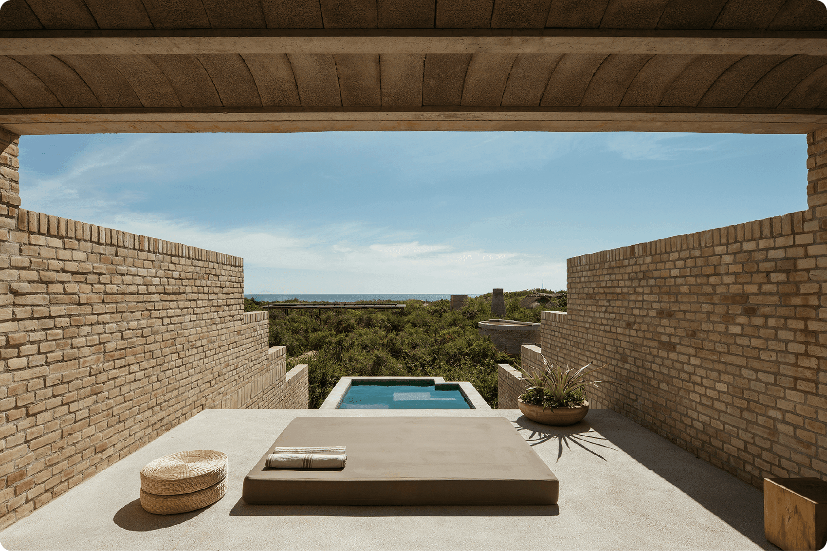 Hotel Terrestre, Mexico — Rooftop terrace with concrete daybed, plunge pool, brick parapets, and lagoon views beneath pergola.