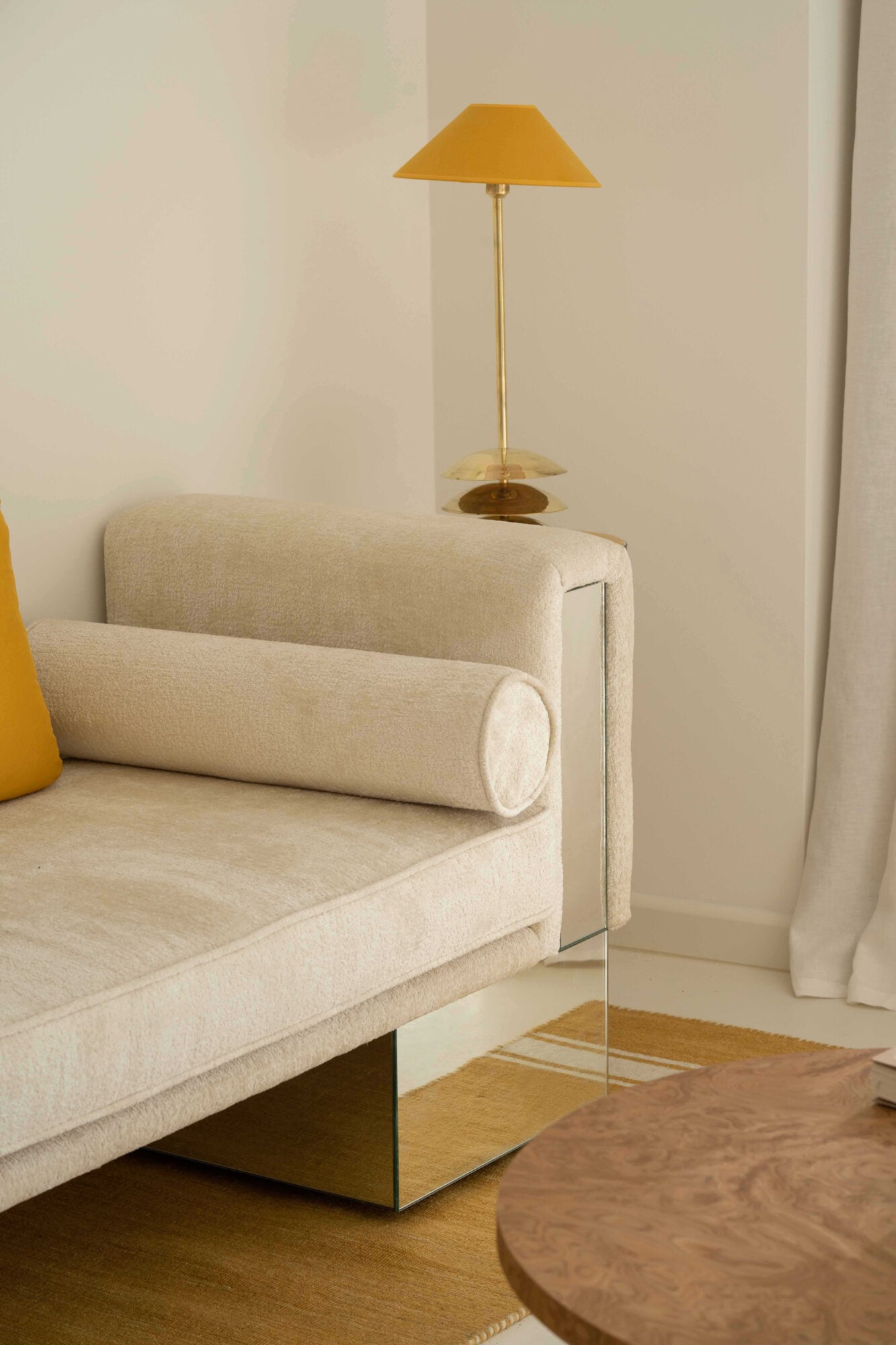 Apollo Palm, Europe — Minimalist hotel room with cream upholstered armchair, brass floor lamp with ochre shade, and wooden side table against neutral walls.