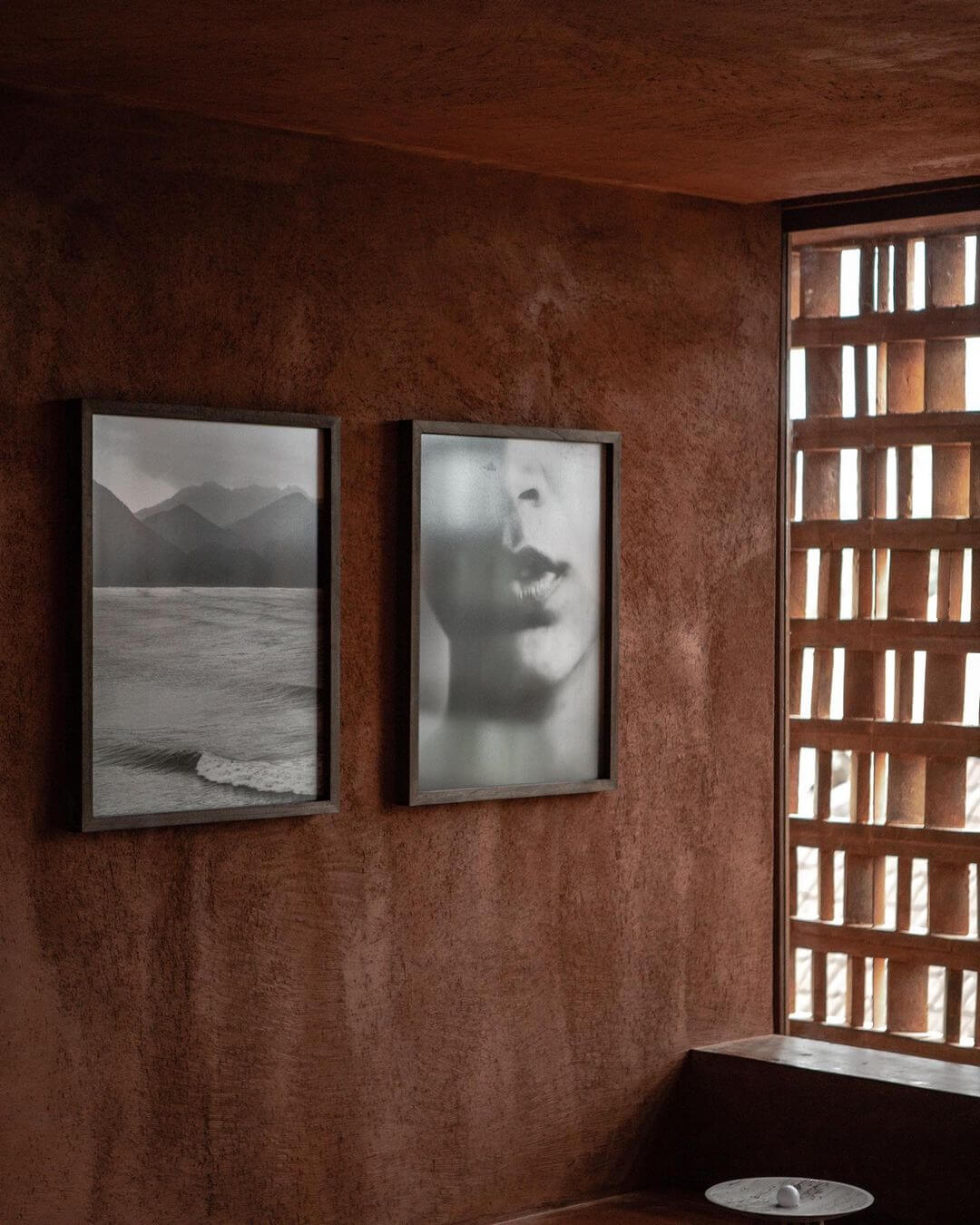 Further Hotel, Asia — Terracotta plaster walls frame black and white photography beside wooden lattice window with diffused natural light.
