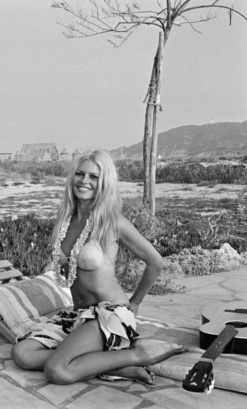 Epi 1959, Europe — Woman in vintage beachwear posed outdoors with bare tree, rolling hills, and mid-century architecture in soft natural light.