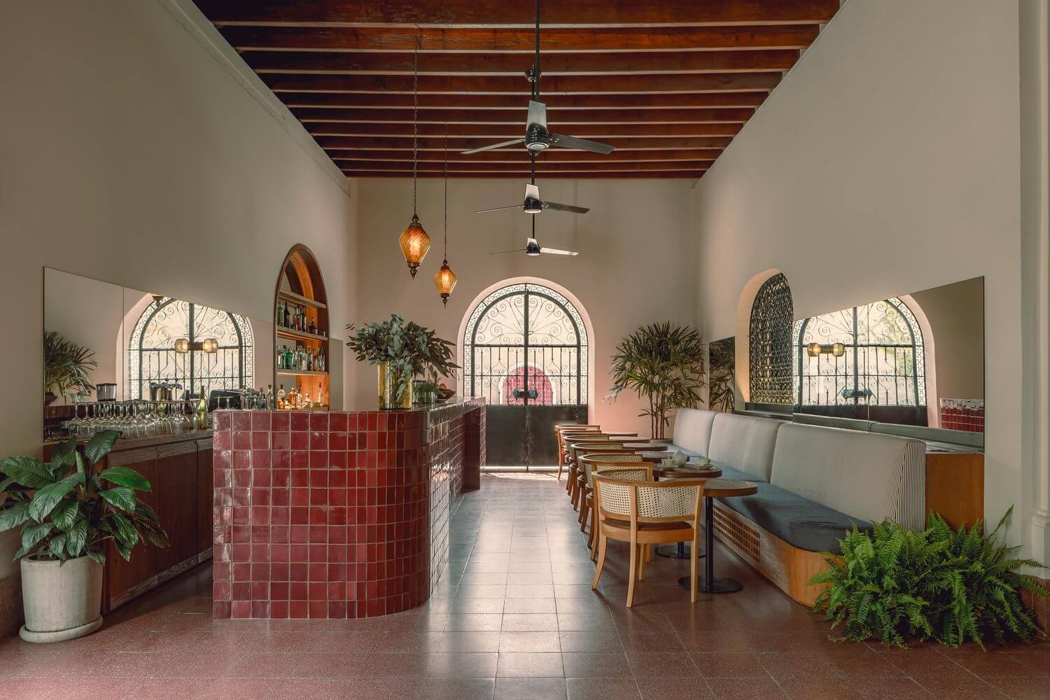 Baja Club, Mexico — Arched windows frame coastal views in candlelit bar with terracotta tilework, wooden beams, and mid-century seating.