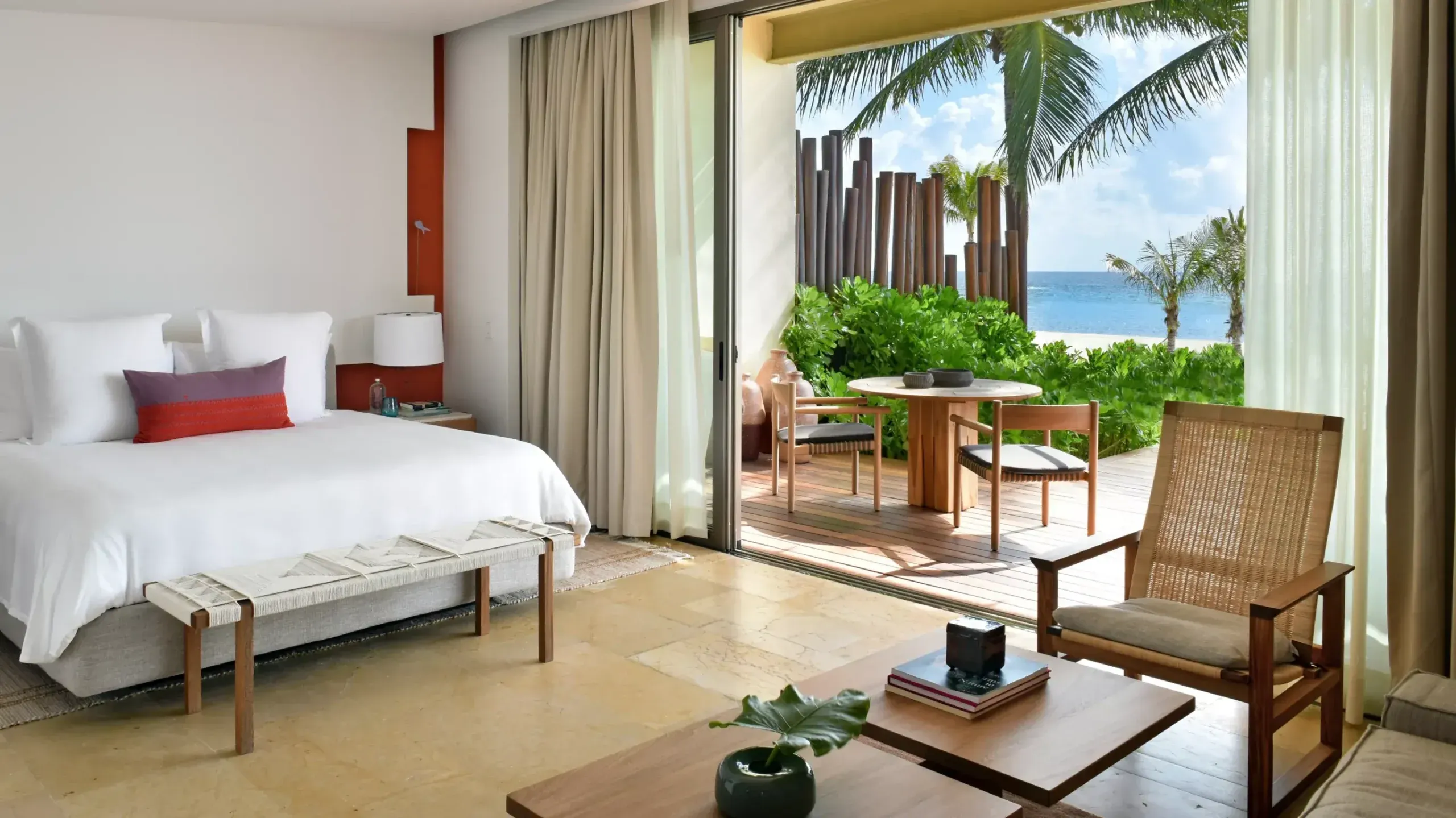 Rosewood Mayakoba, Mexico — Beachfront suite with white linens, teak furnishings, palm views, and ocean-facing terrace with wooden deck and tropical landscape.