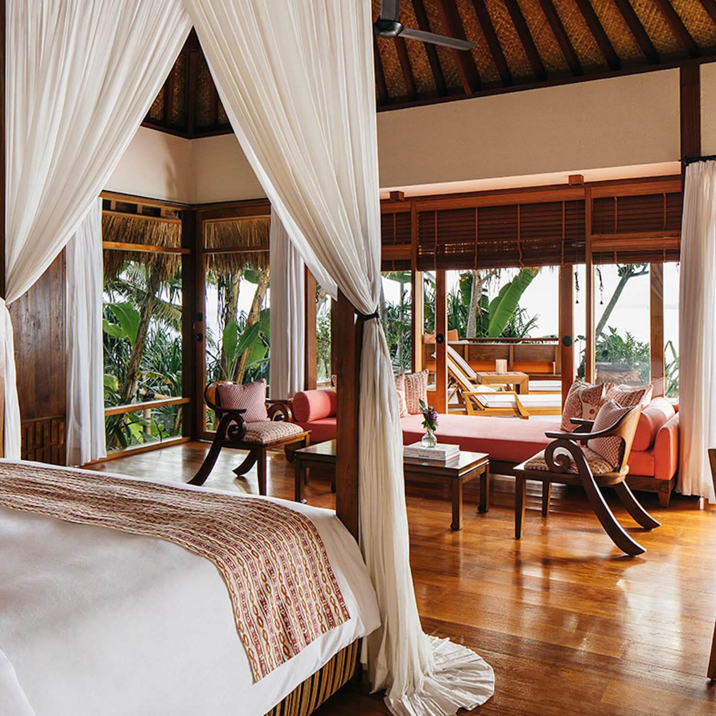 NIHI Sumba, Asia — Canopied bed with cream drapes overlooks tropical veranda, wooden architecture with coral furnishings and ocean views.